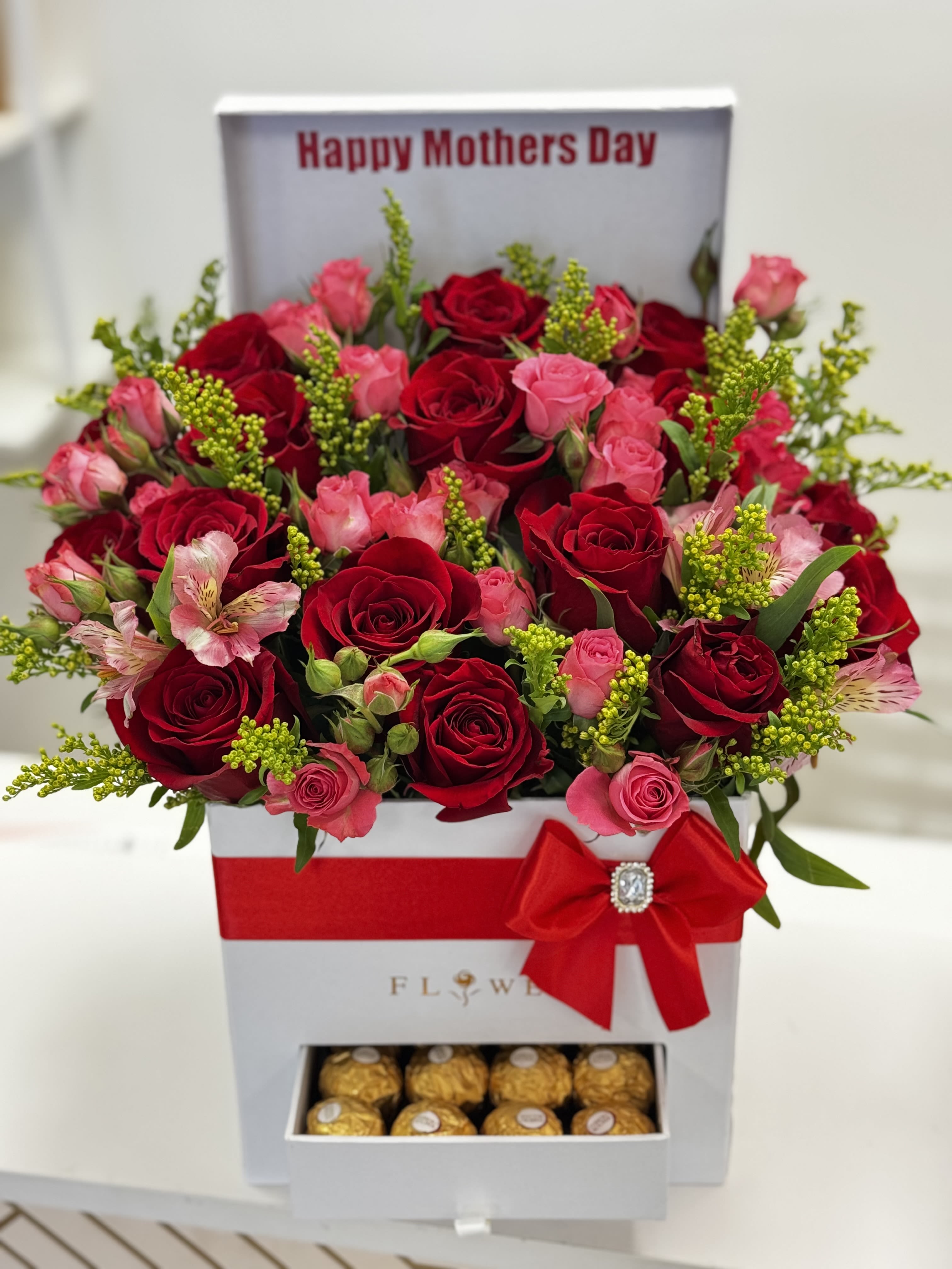 Red and pink roses in a gift box with chocolates and a red bow