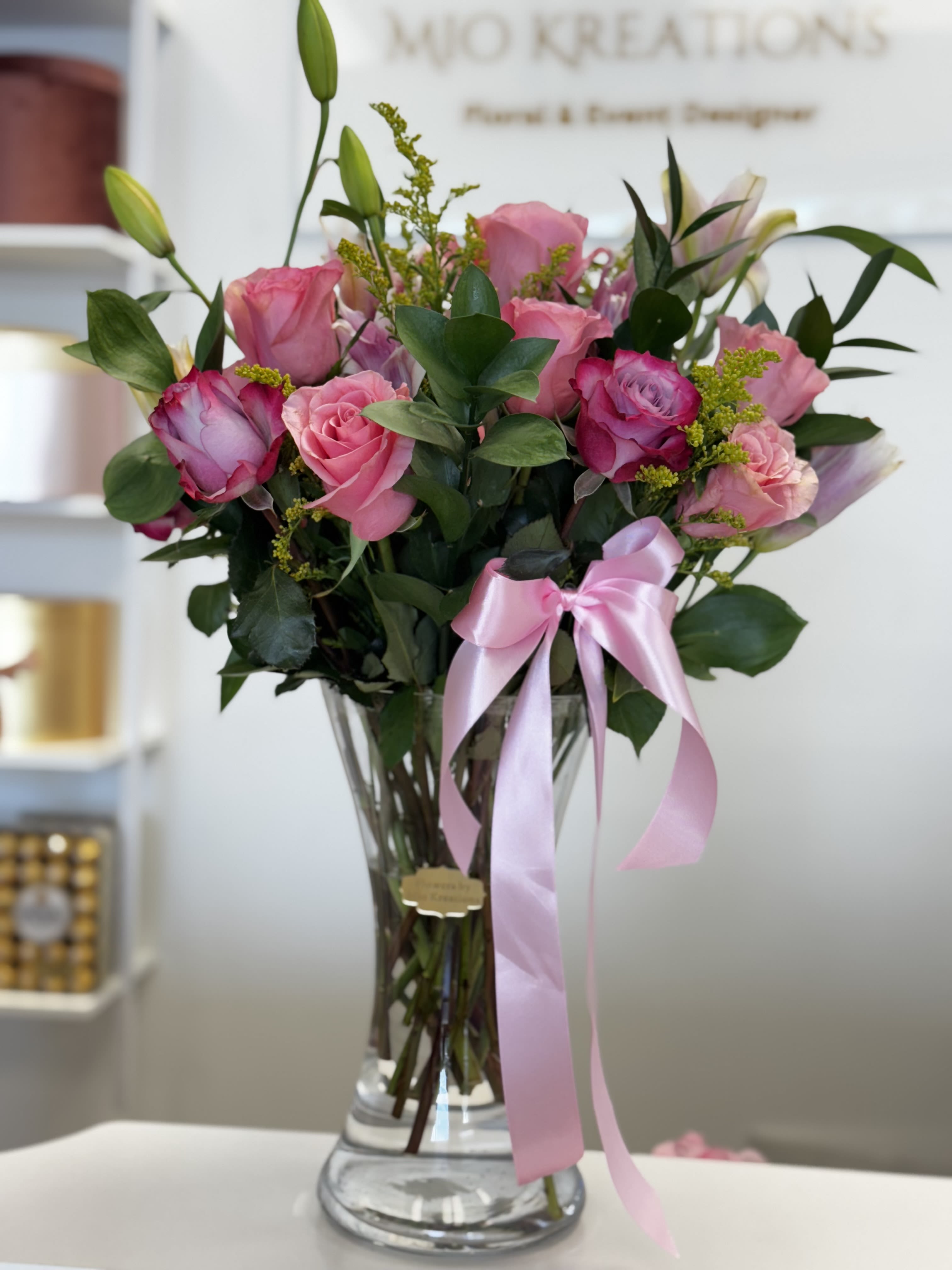 Pink roses in a clear glass vase with a pink ribbon