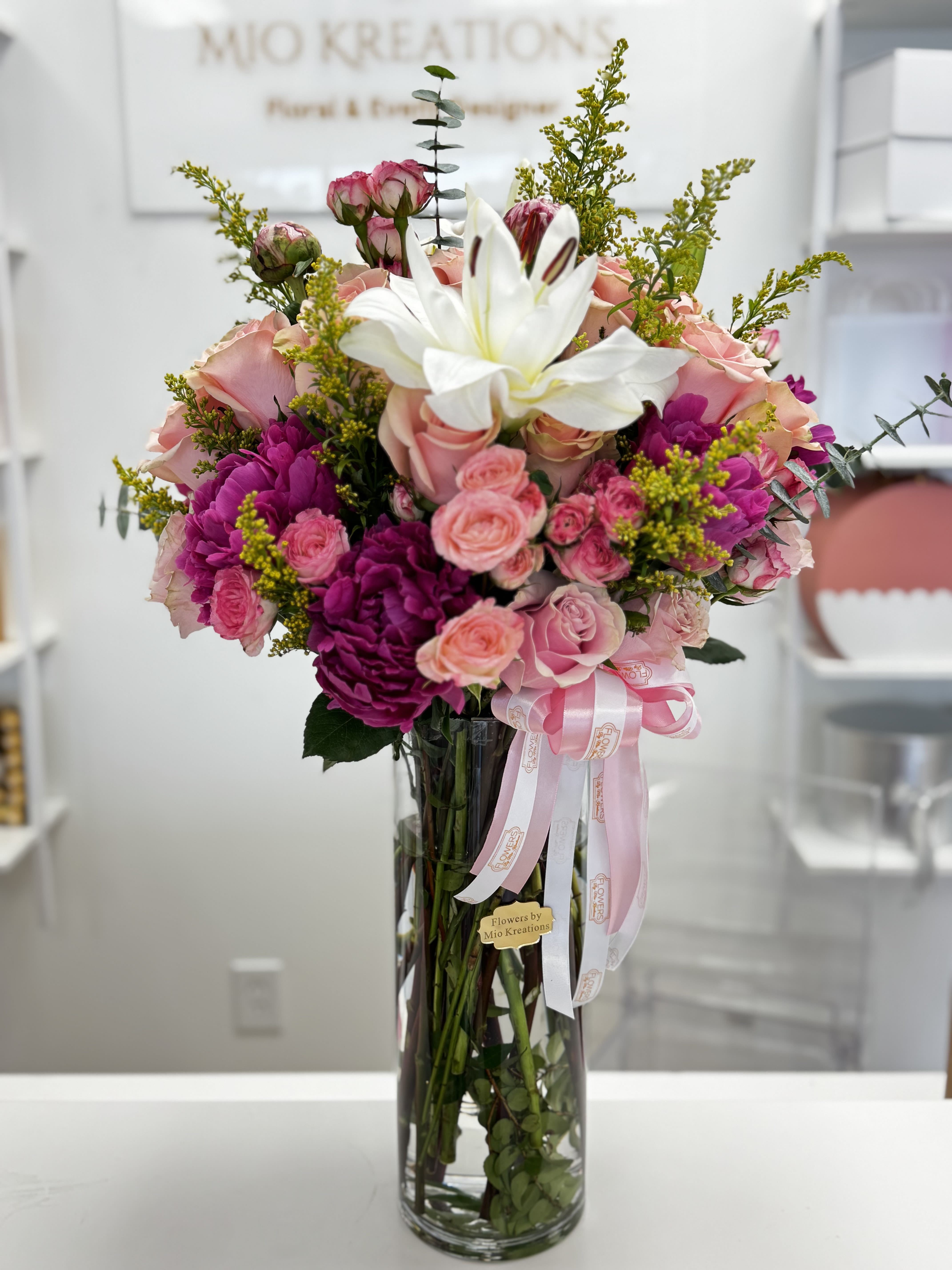 Pink and white flower bouquet in a tall glass vase with ribbon