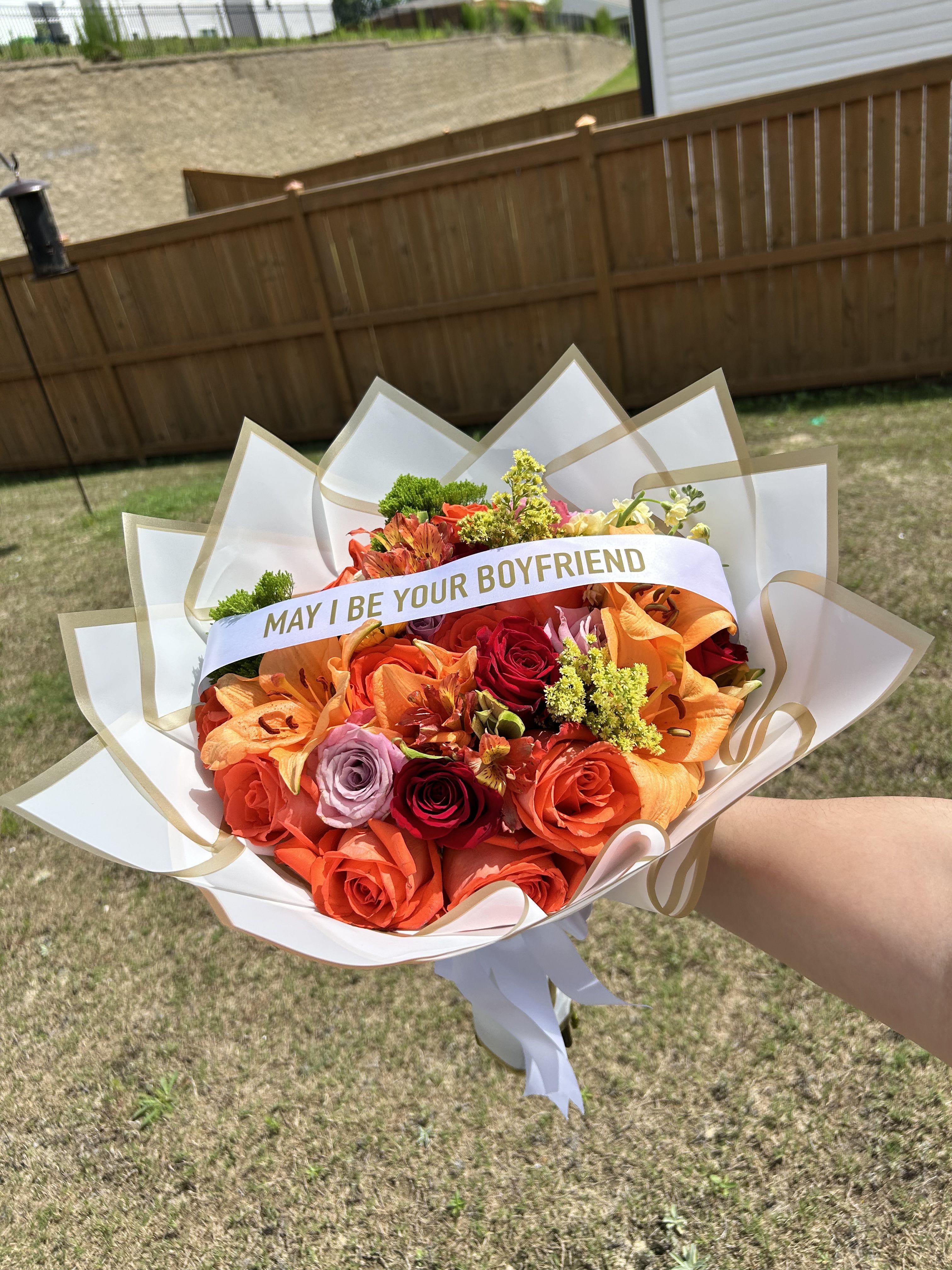Bouquet of orange and red roses with a "MAY I BE YOUR BOYFRIEND" sash