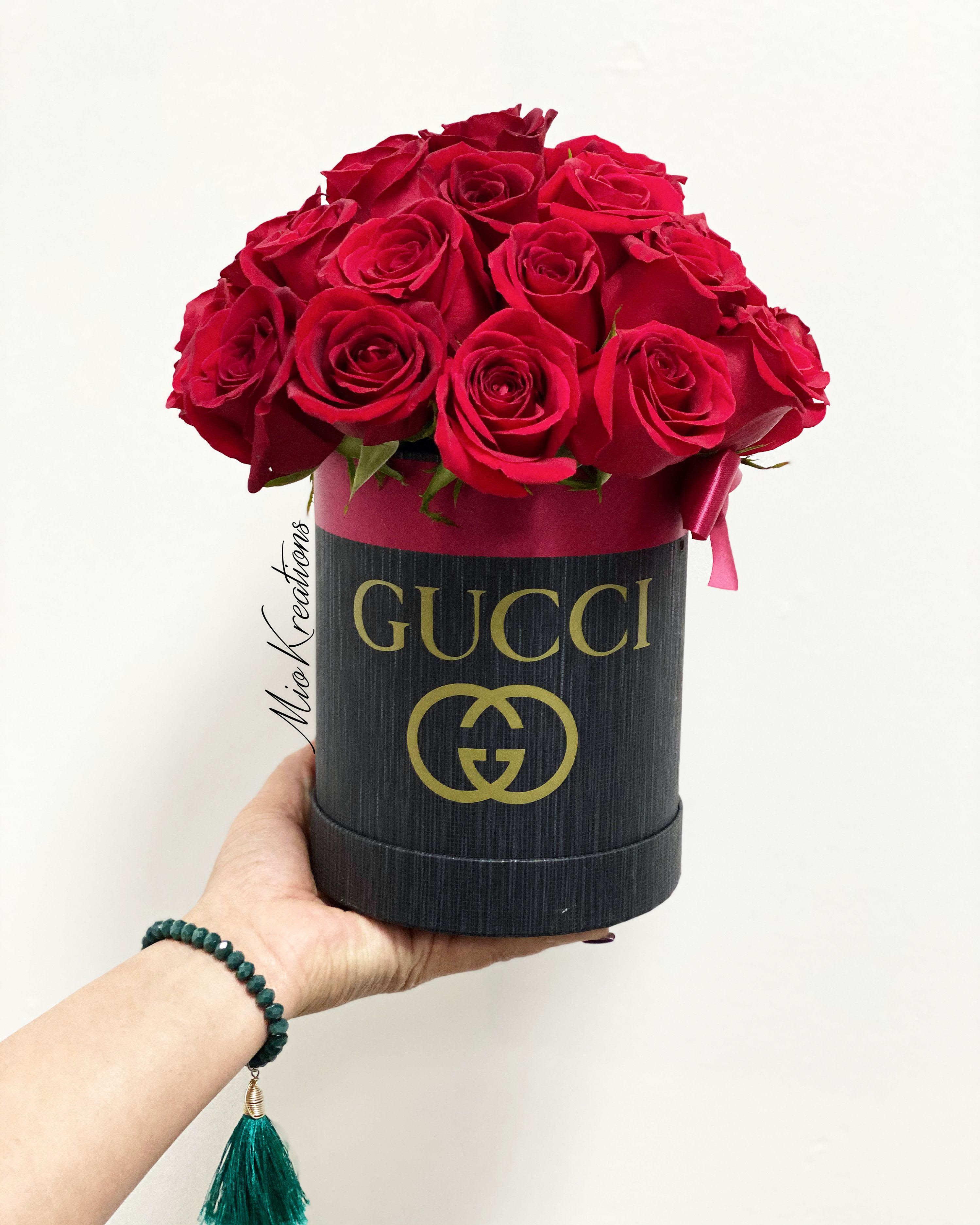 Red roses arranged in a black Gucci hat box