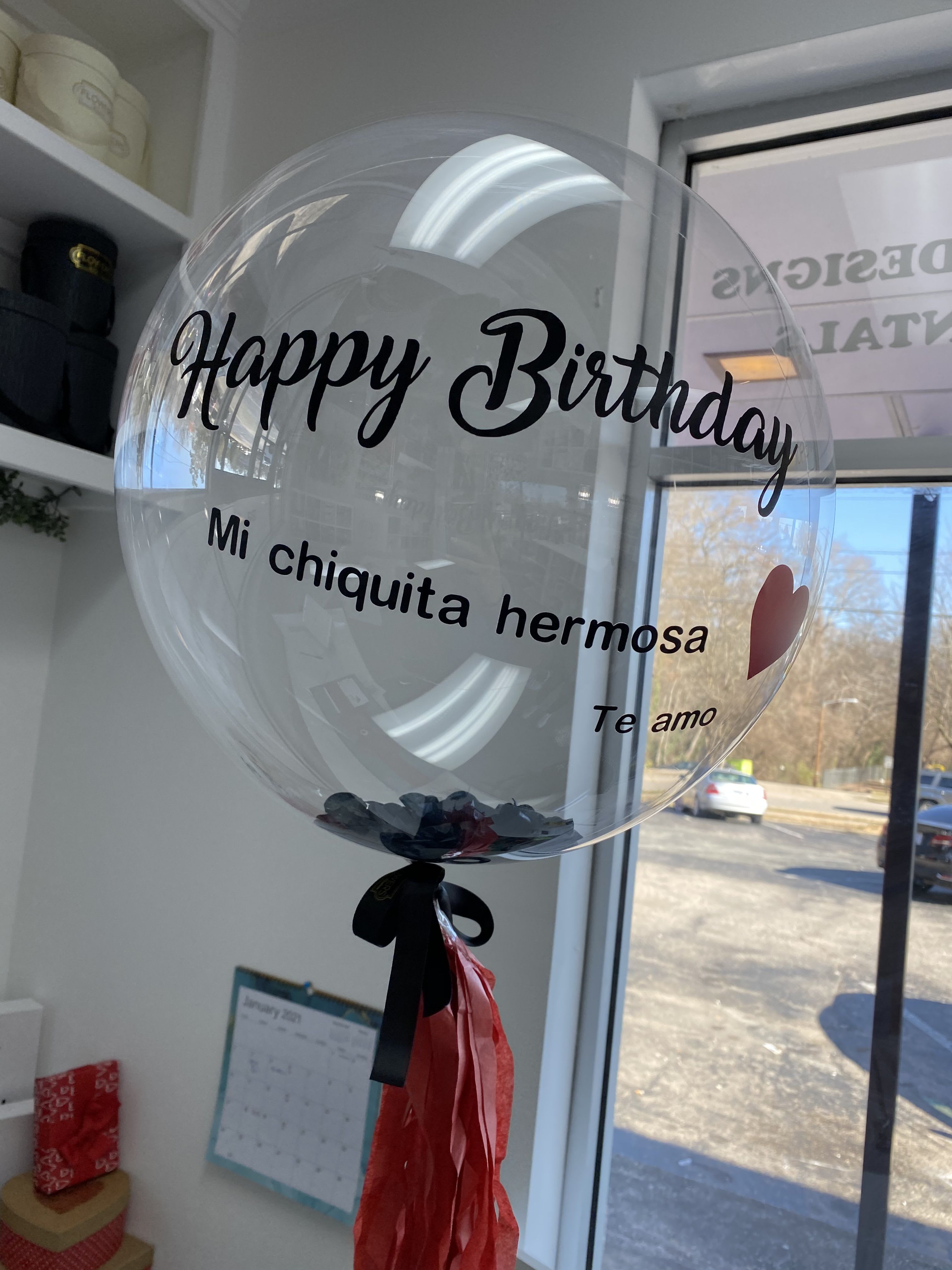 Clear birthday balloon with black text and red tassels