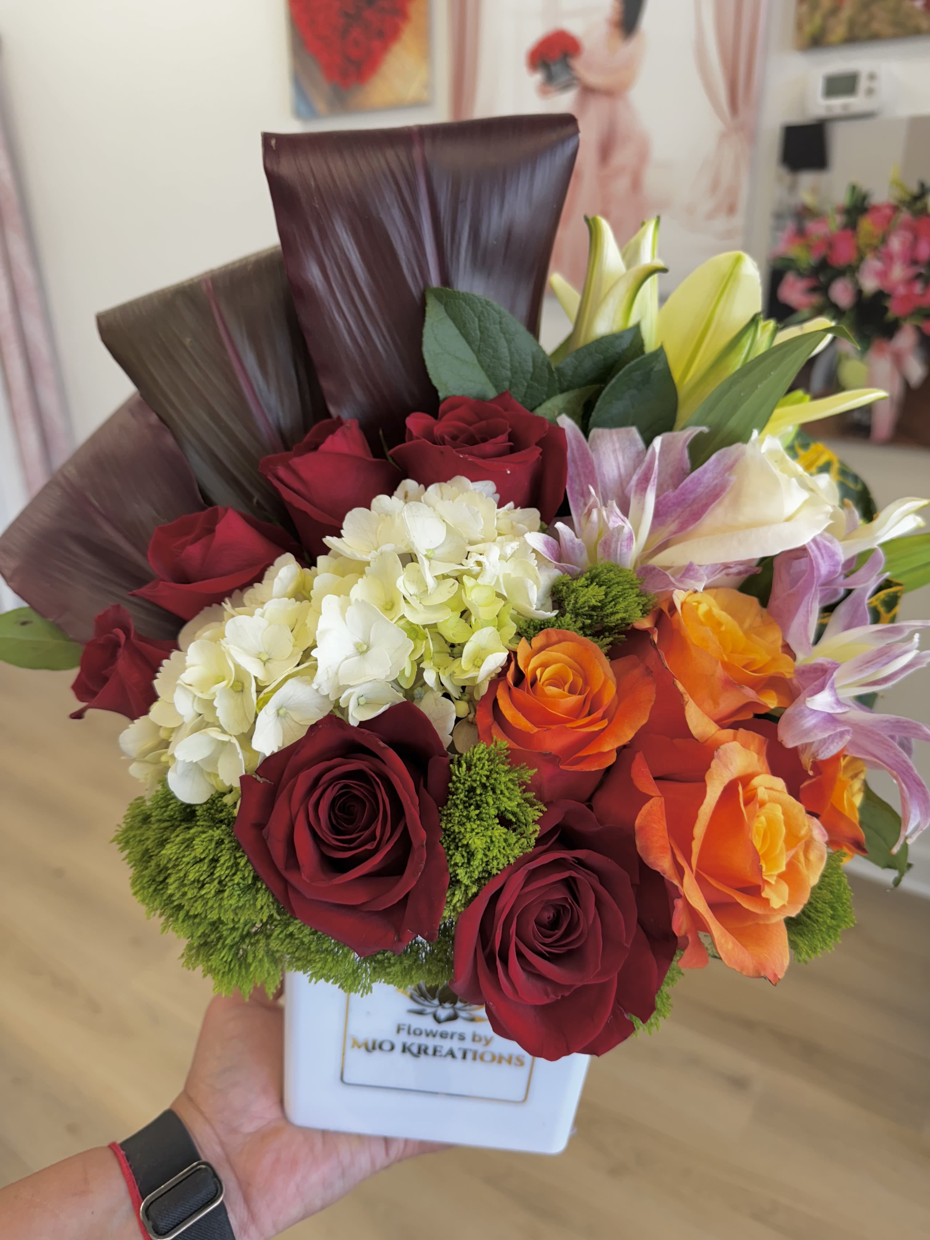 Bouquet of red and orange roses with white hydrangea in a white vase