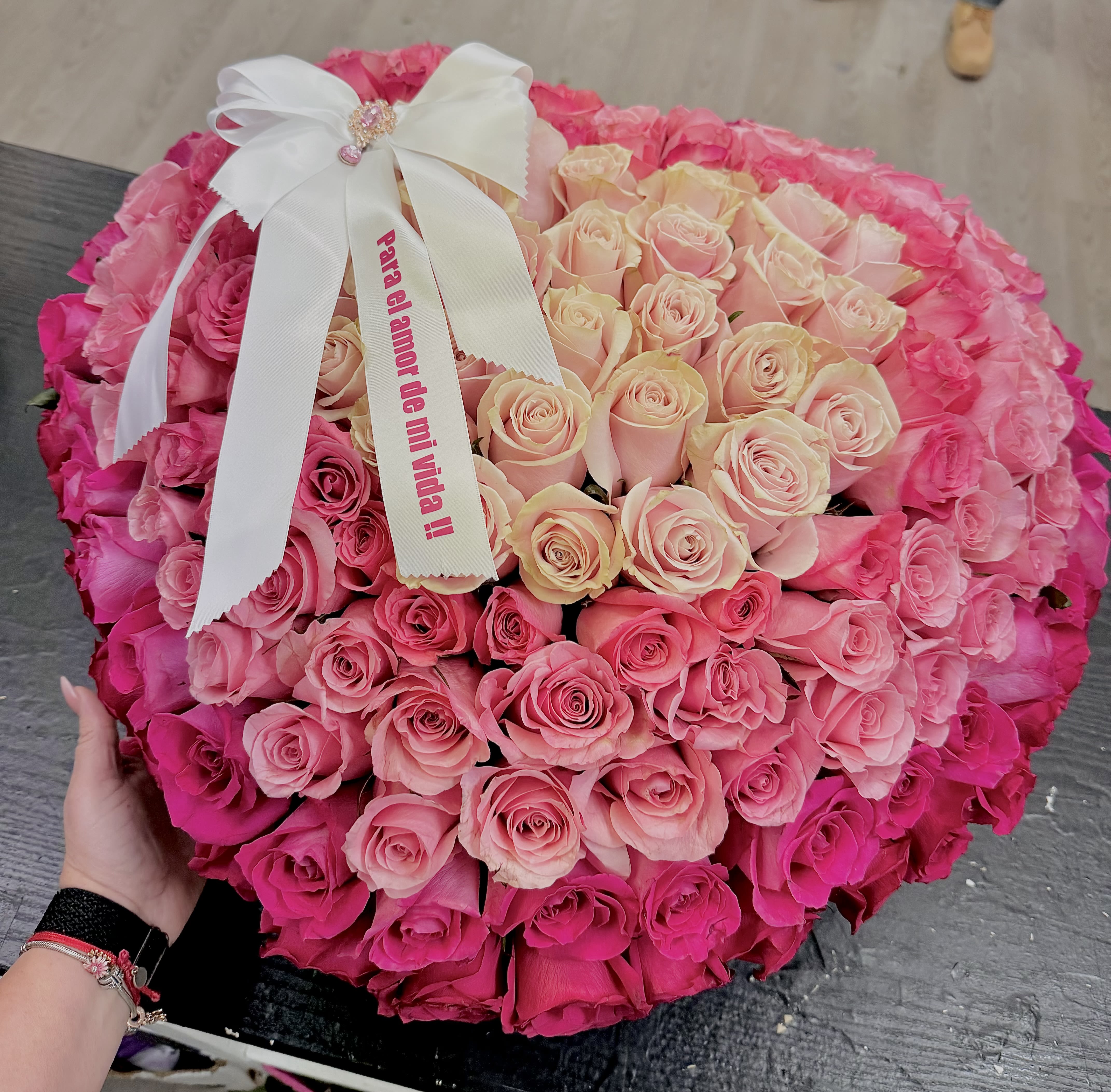 Large round bouquet of pink and blush roses with a white ribbon bow