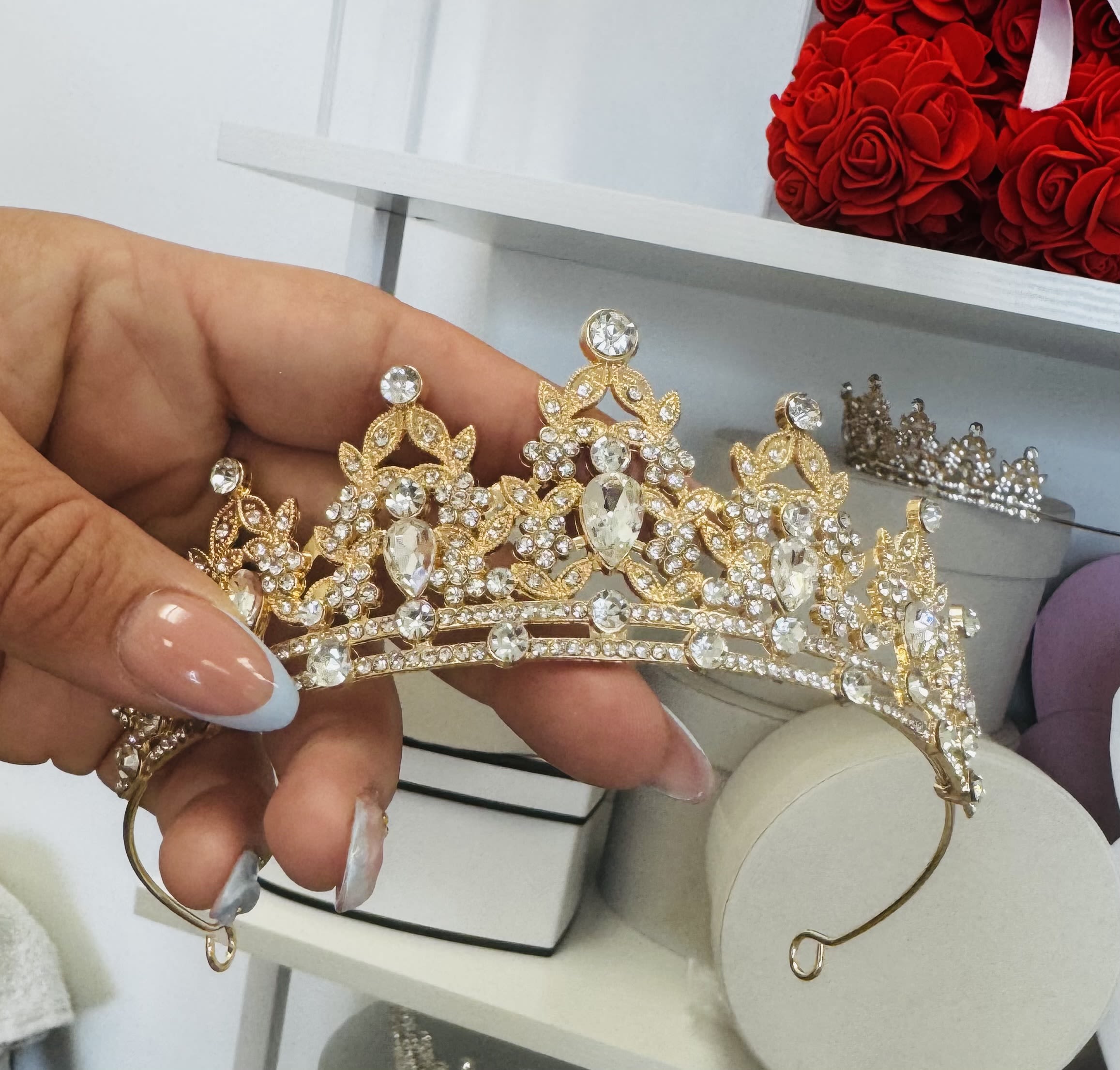 Hand holding a gold rhinestone tiara with clear crystals