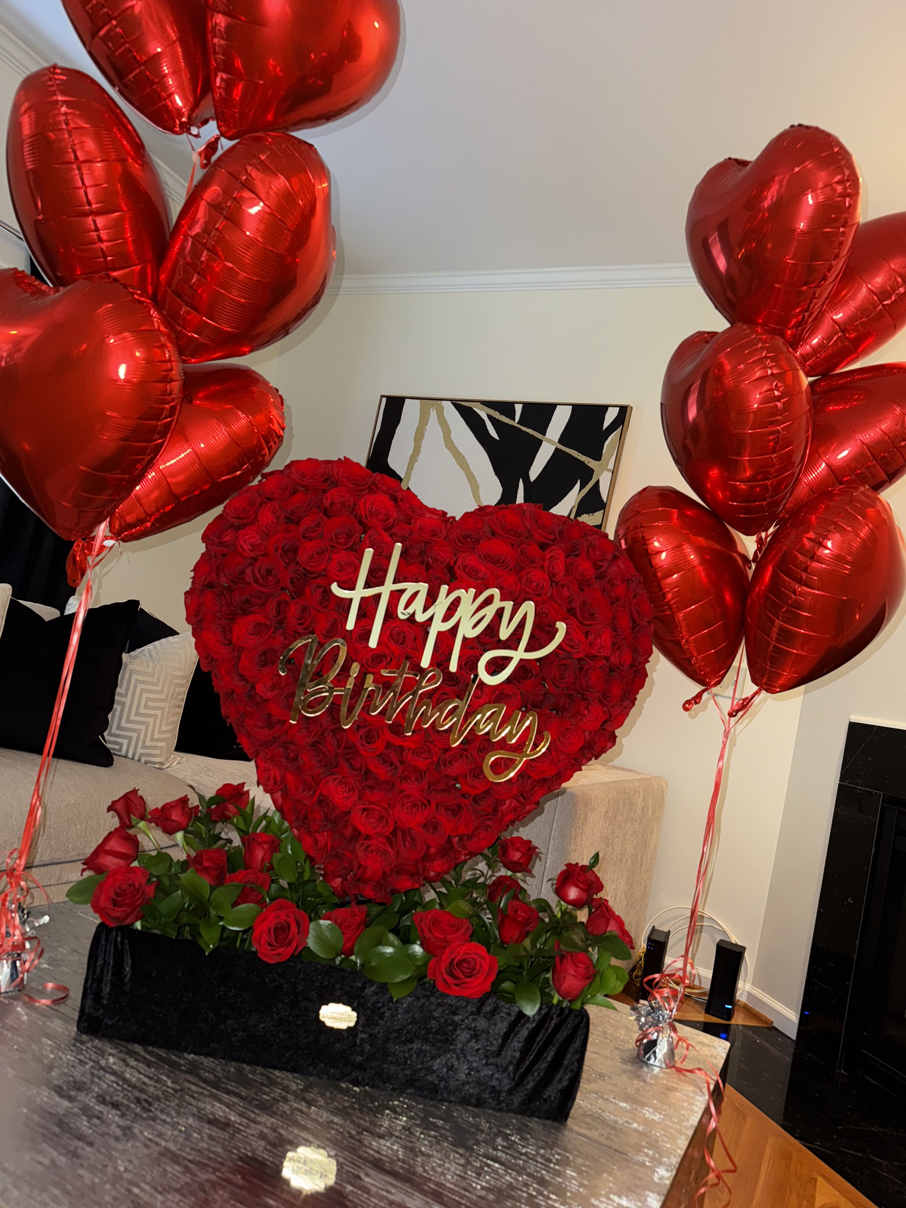 Heart-shaped rose arrangement with red balloons and a Happy Birthday sign