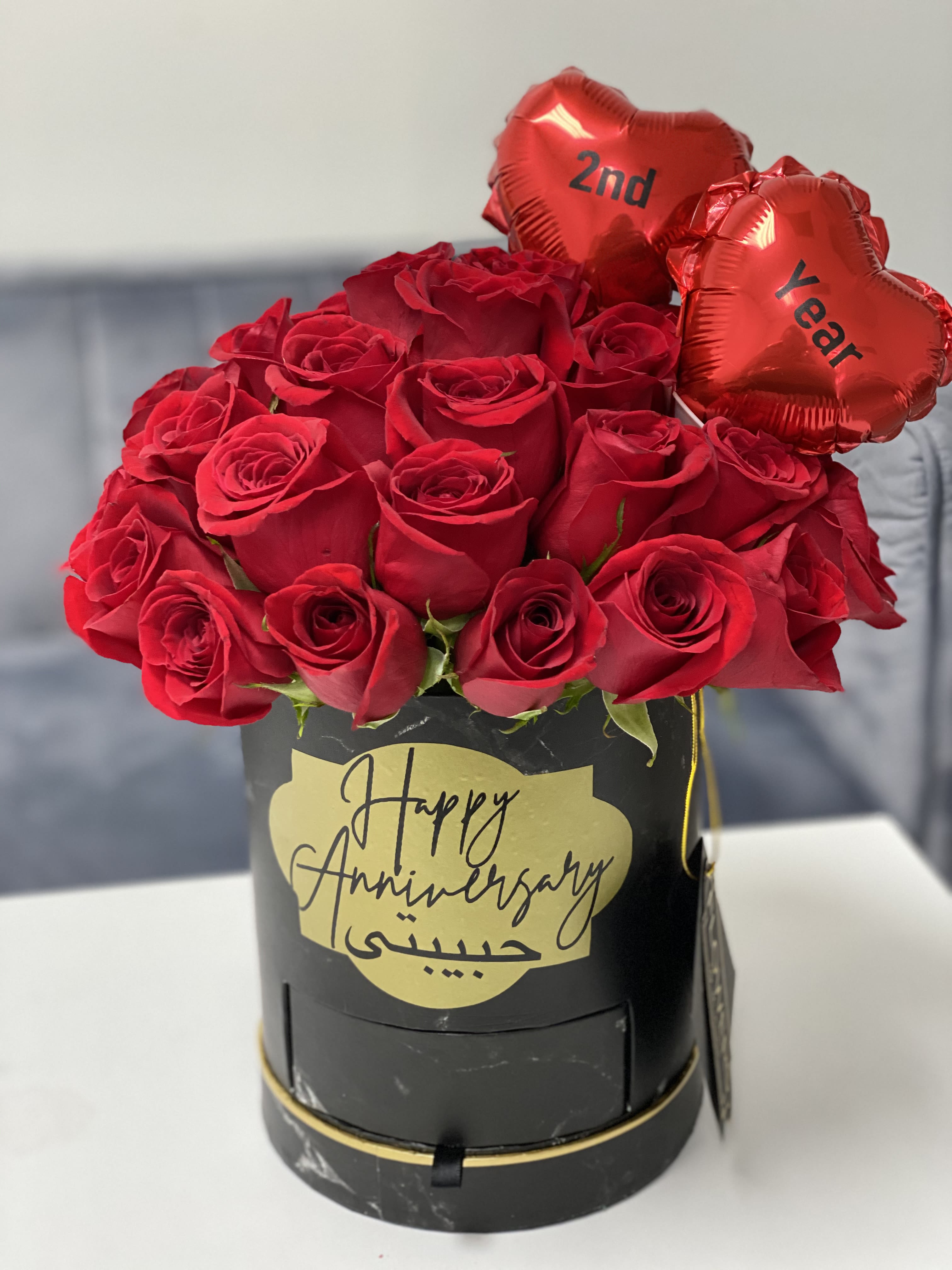 Red roses in a black box with two heart balloons