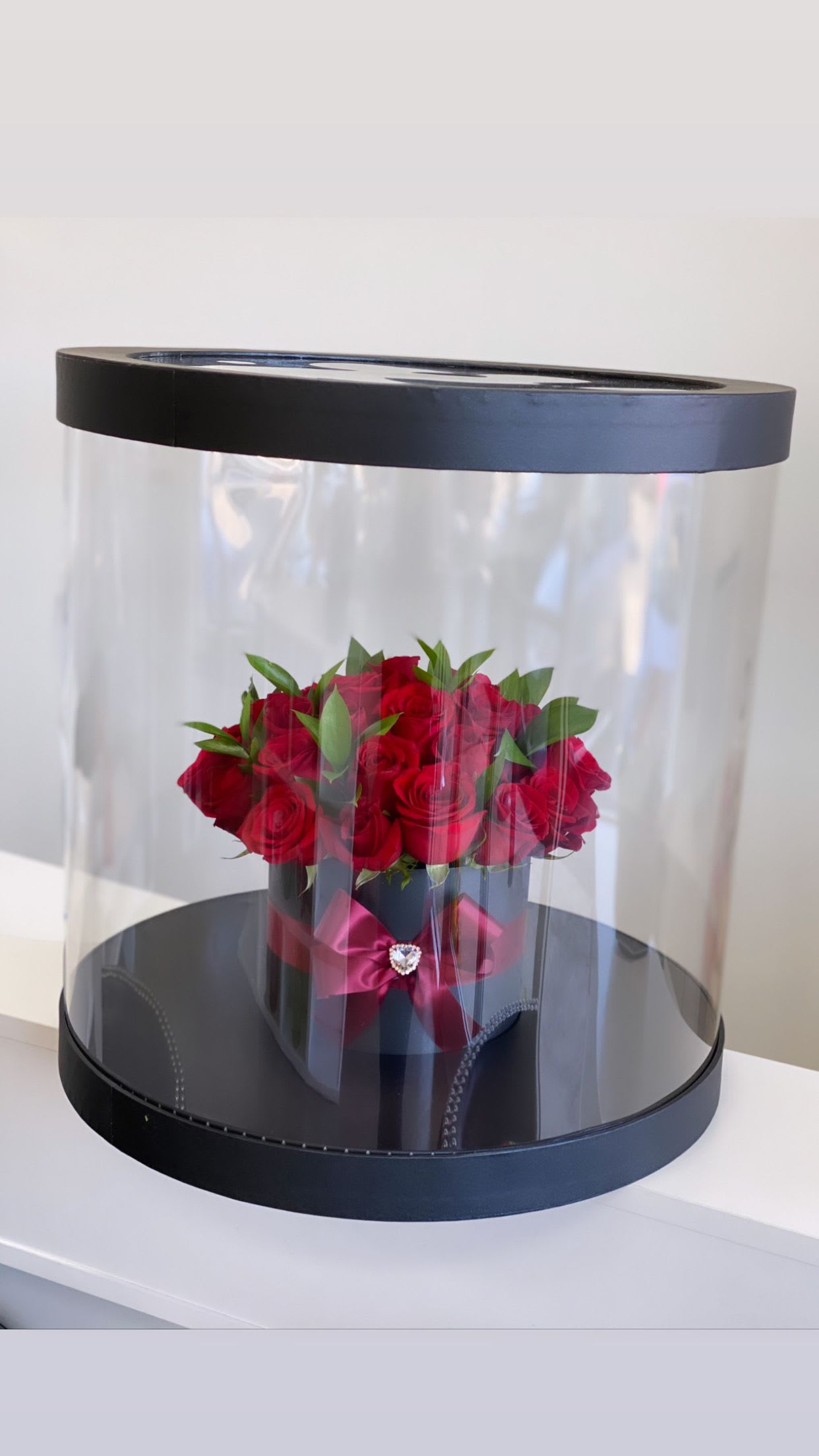 Red roses in a black hatbox with a clear dome cover