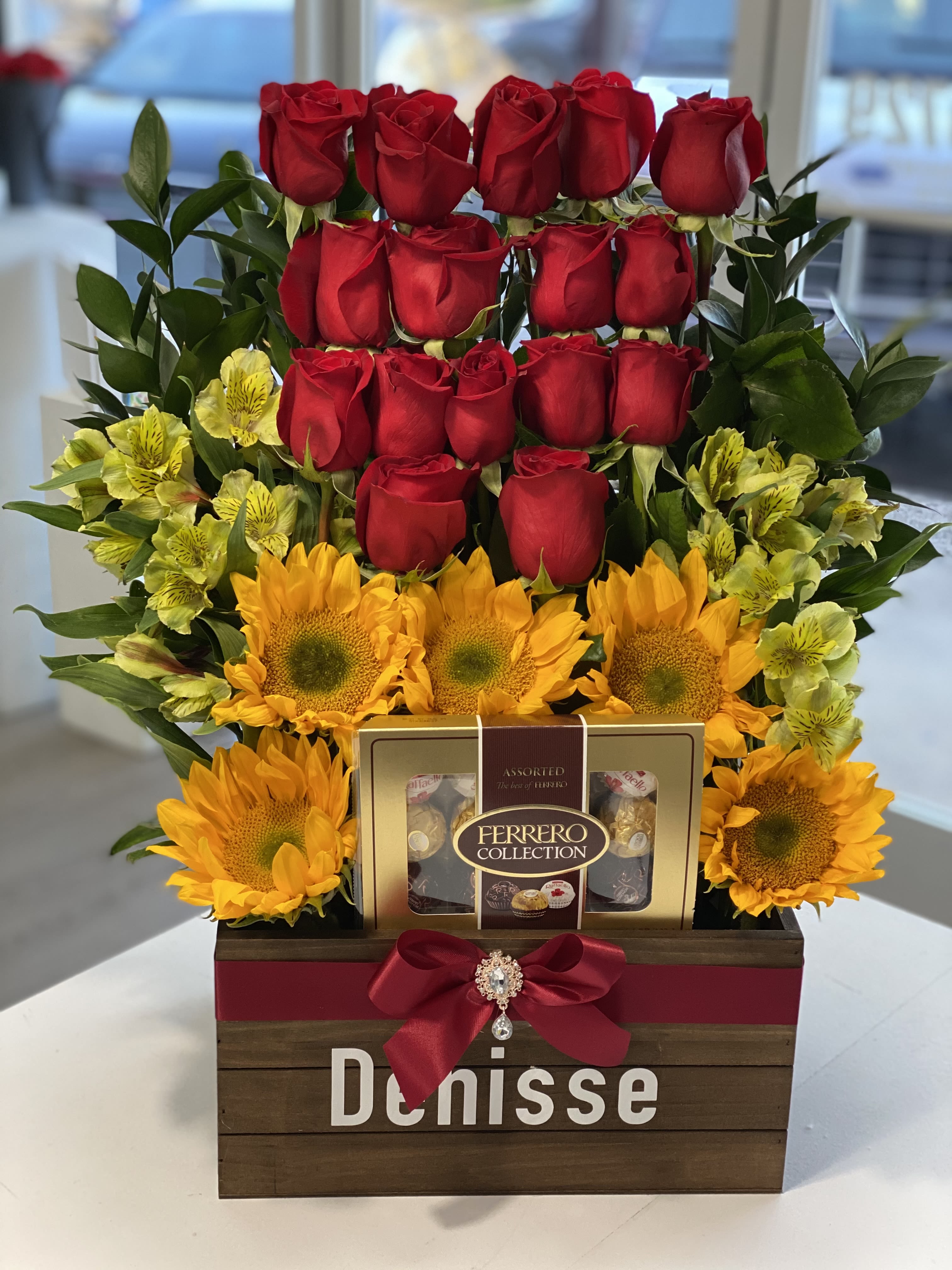 Red roses and sunflowers arranged with chocolates in a wooden gift box