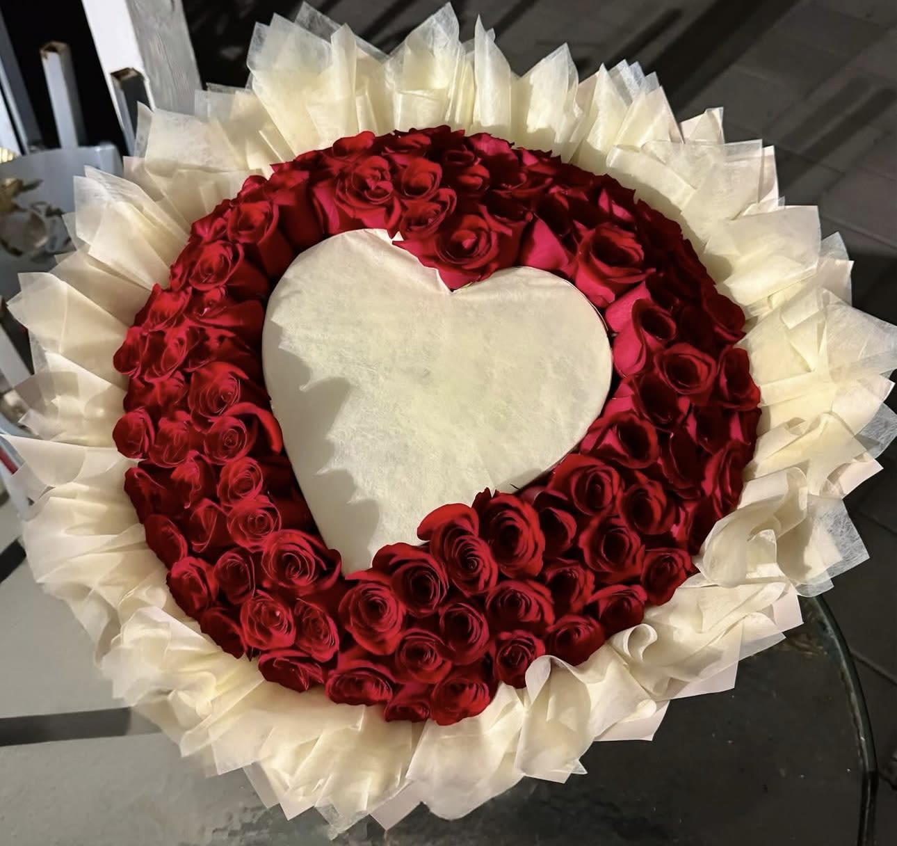 Heart-shaped arrangement of red roses with white wrapping around it