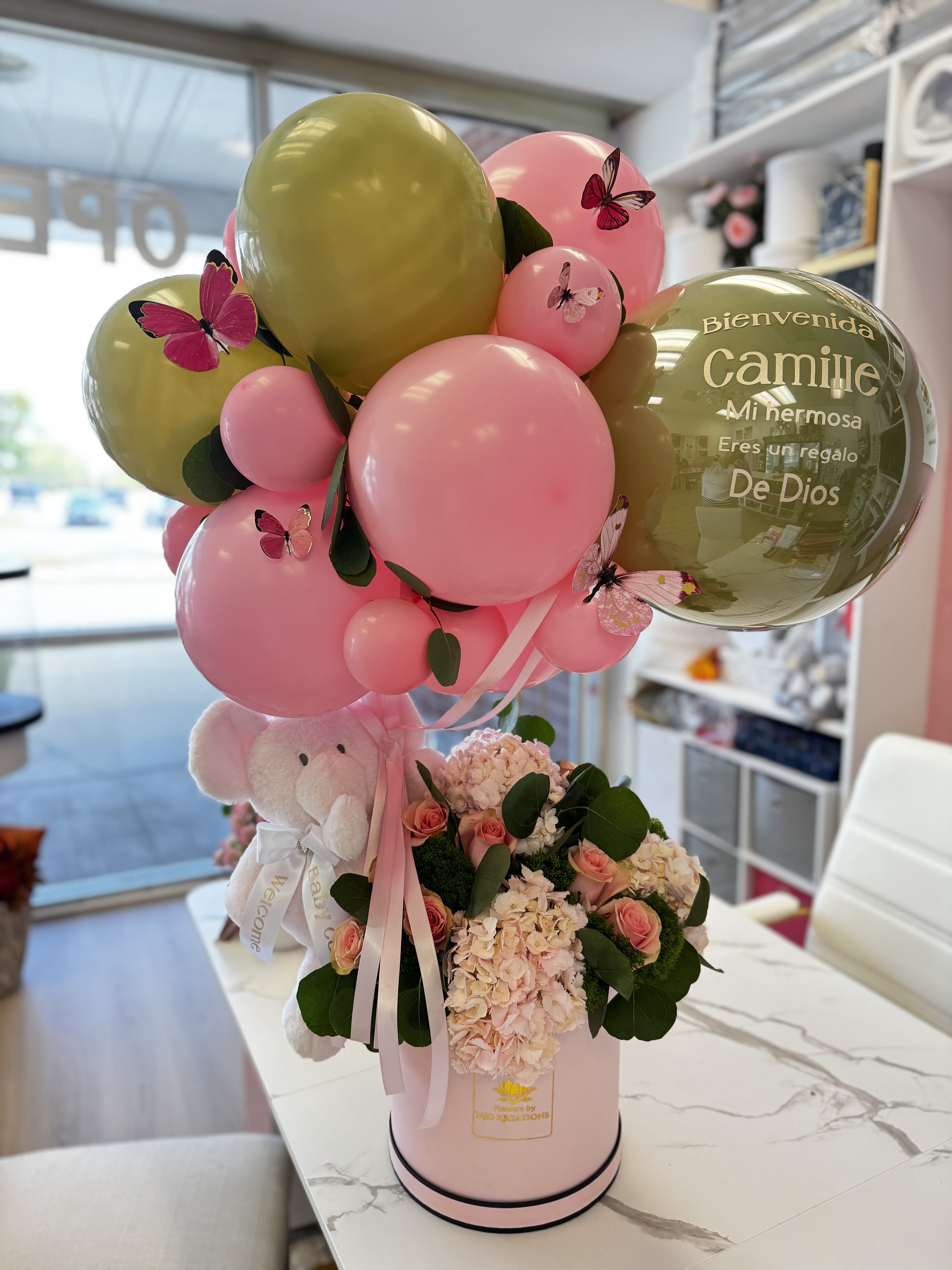 Pink and gold balloon arrangement with a teddy bear and flowers in a pink box