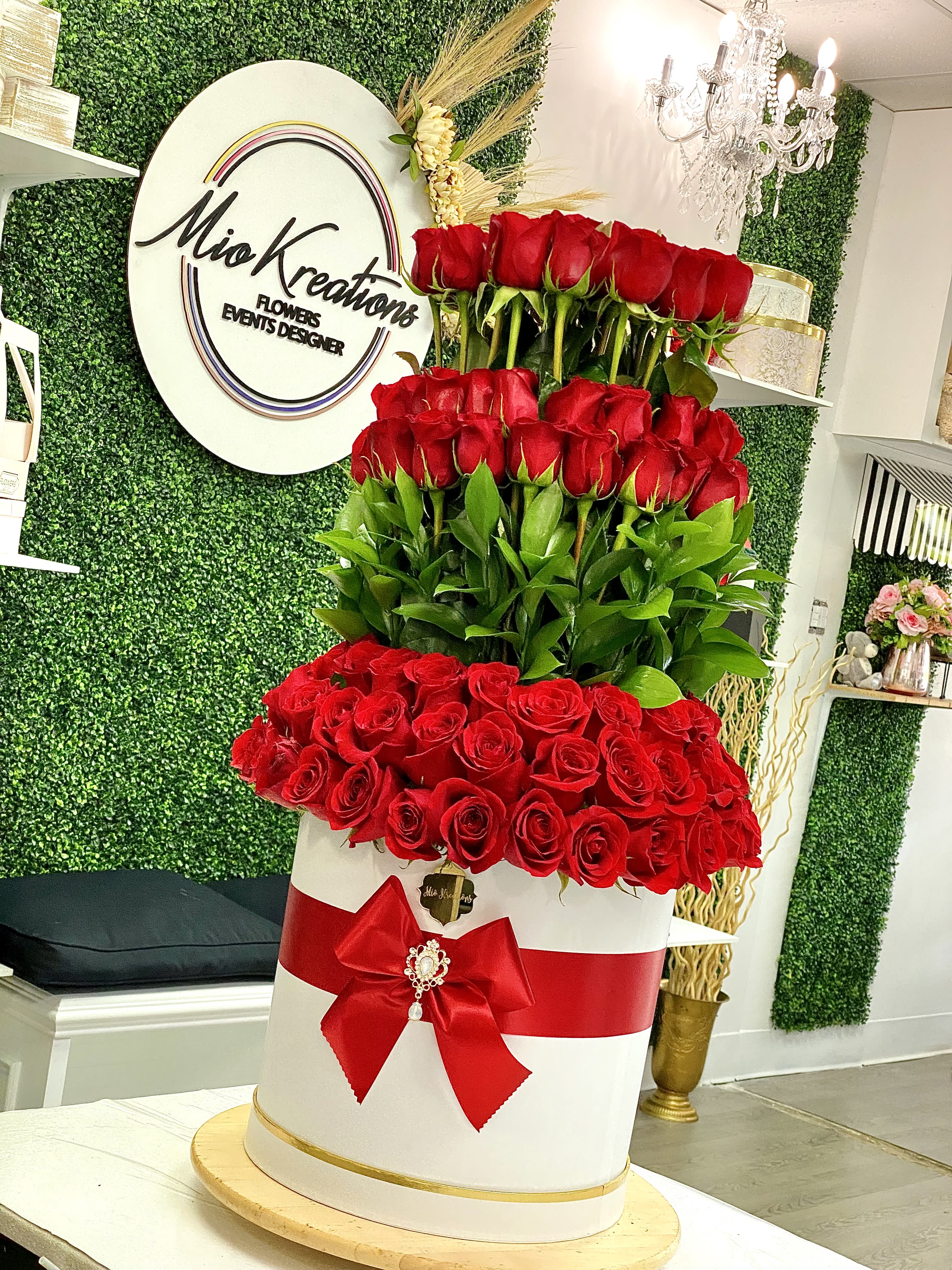 Tall tiered arrangement of red roses in a white box with a red bow