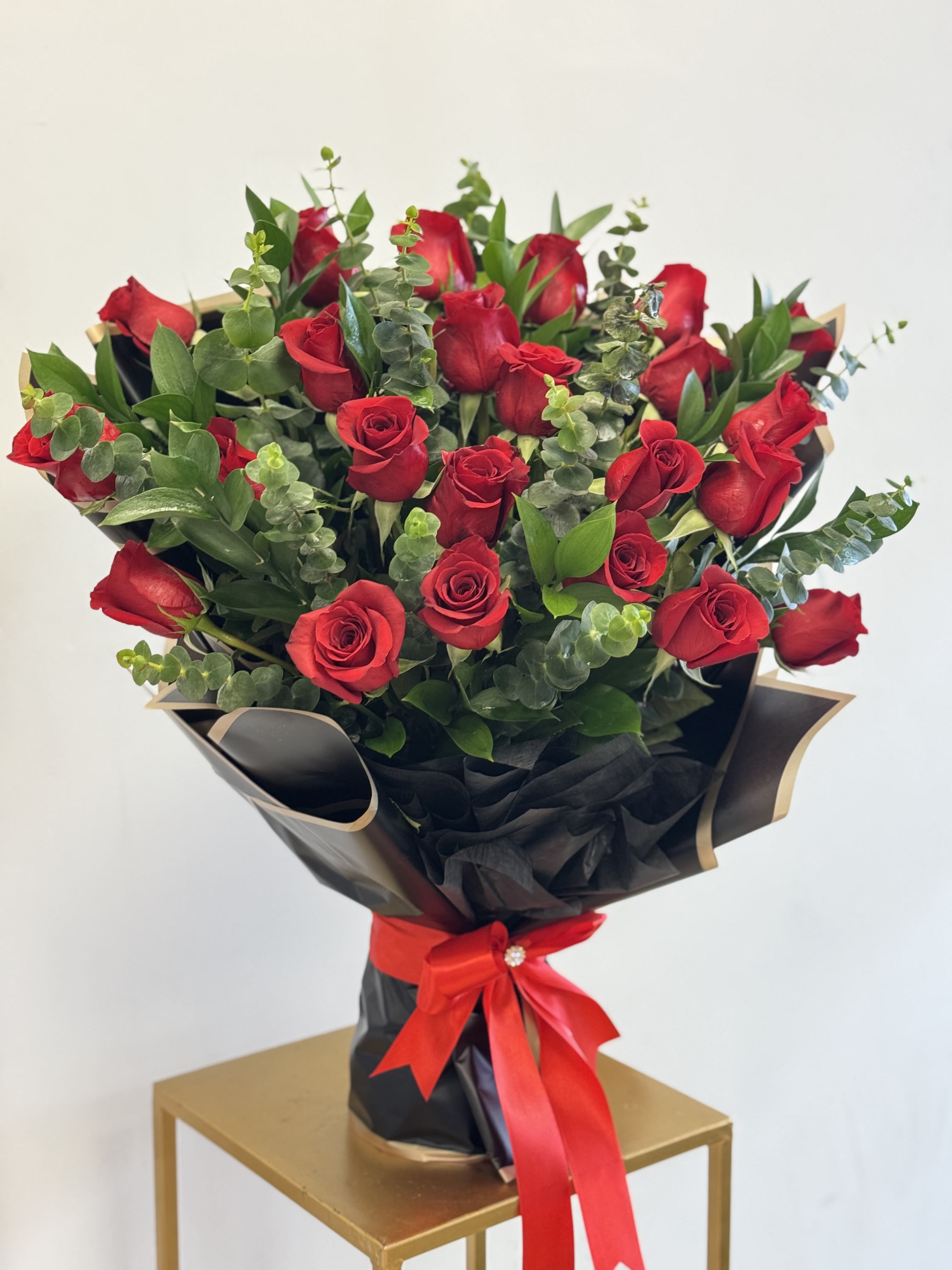 Bouquet of red roses wrapped in black paper with a red ribbon