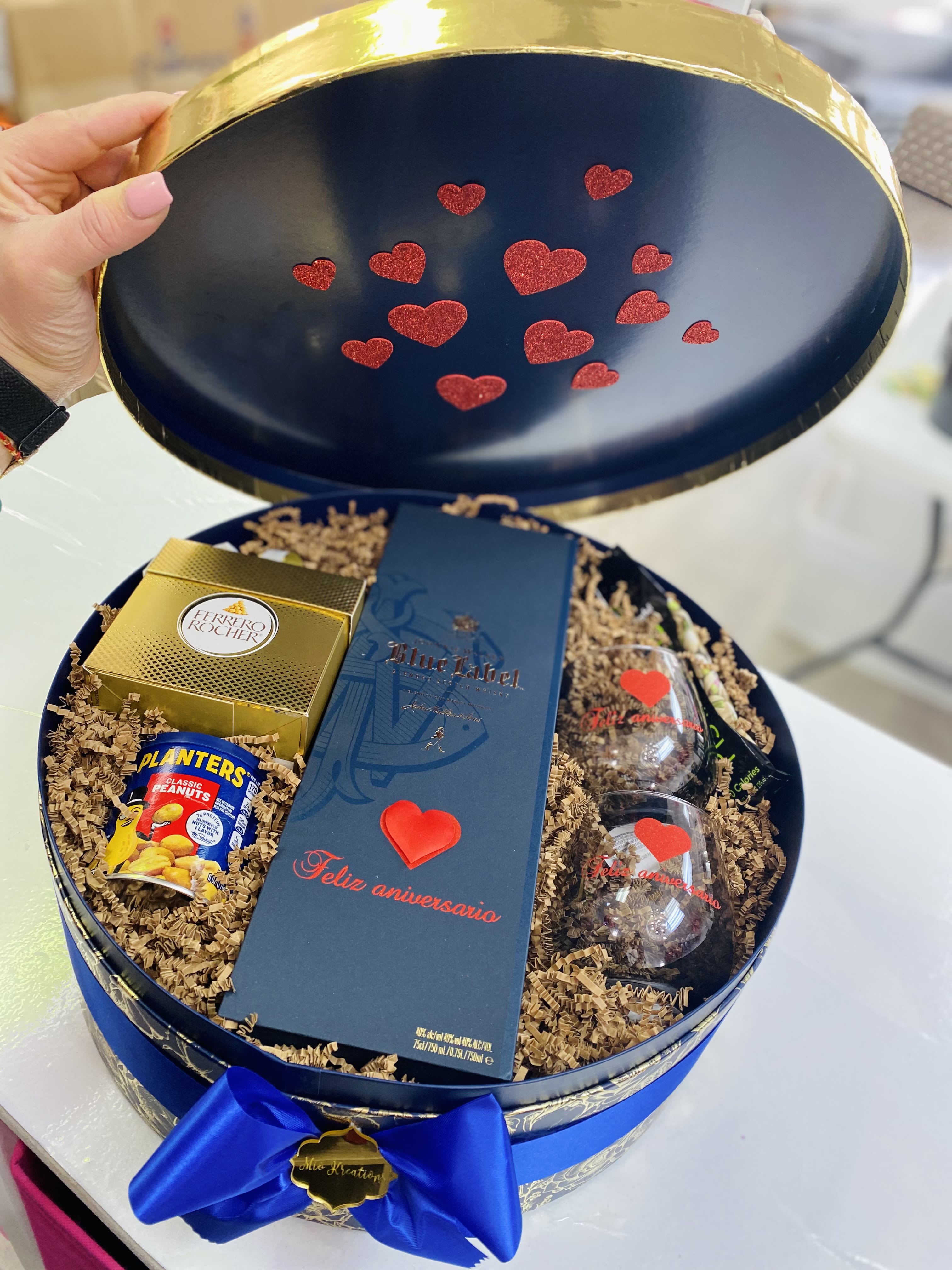 Gift box with chocolates, peanuts, and two glasses inside a round blue case