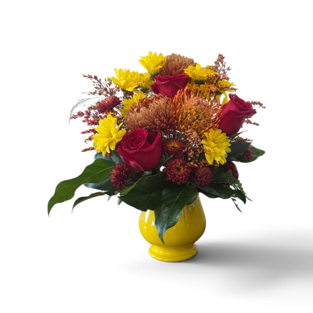 Mixed bouquet of red roses and yellow flowers in a yellow vase