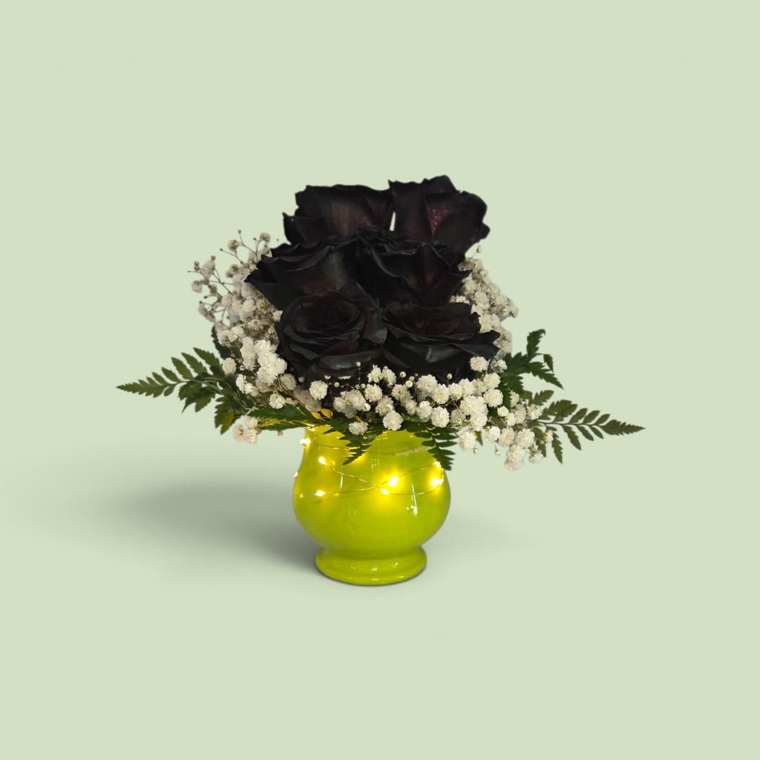 Black roses in a bright yellow vase with white filler flowers
