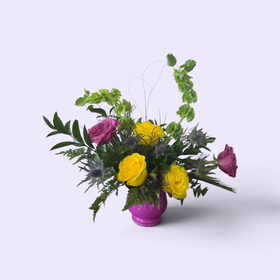 Yellow and purple roses in a magenta vase