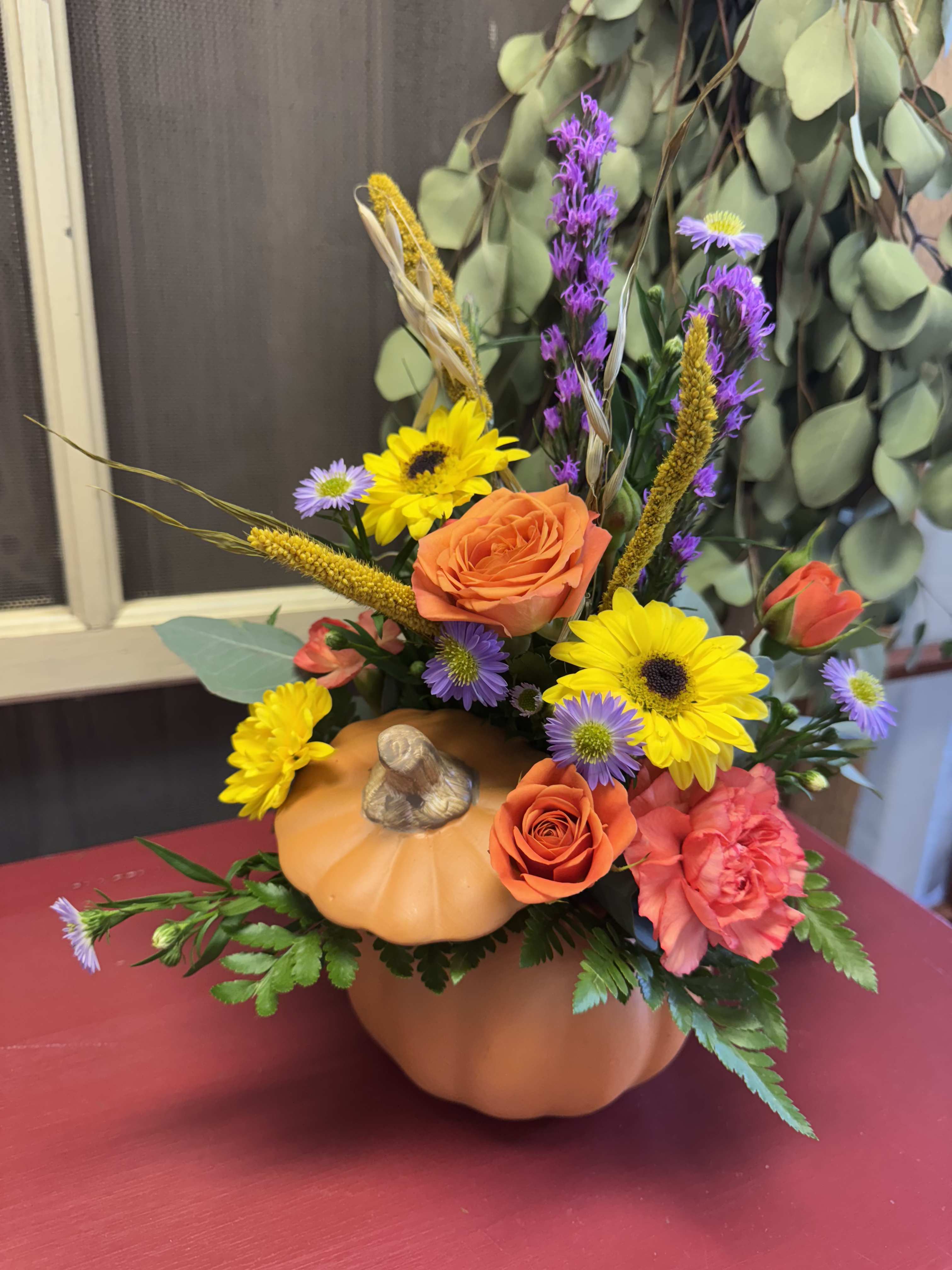 Pumpkin-shaped floral arrangement with orange roses and yellow daisies