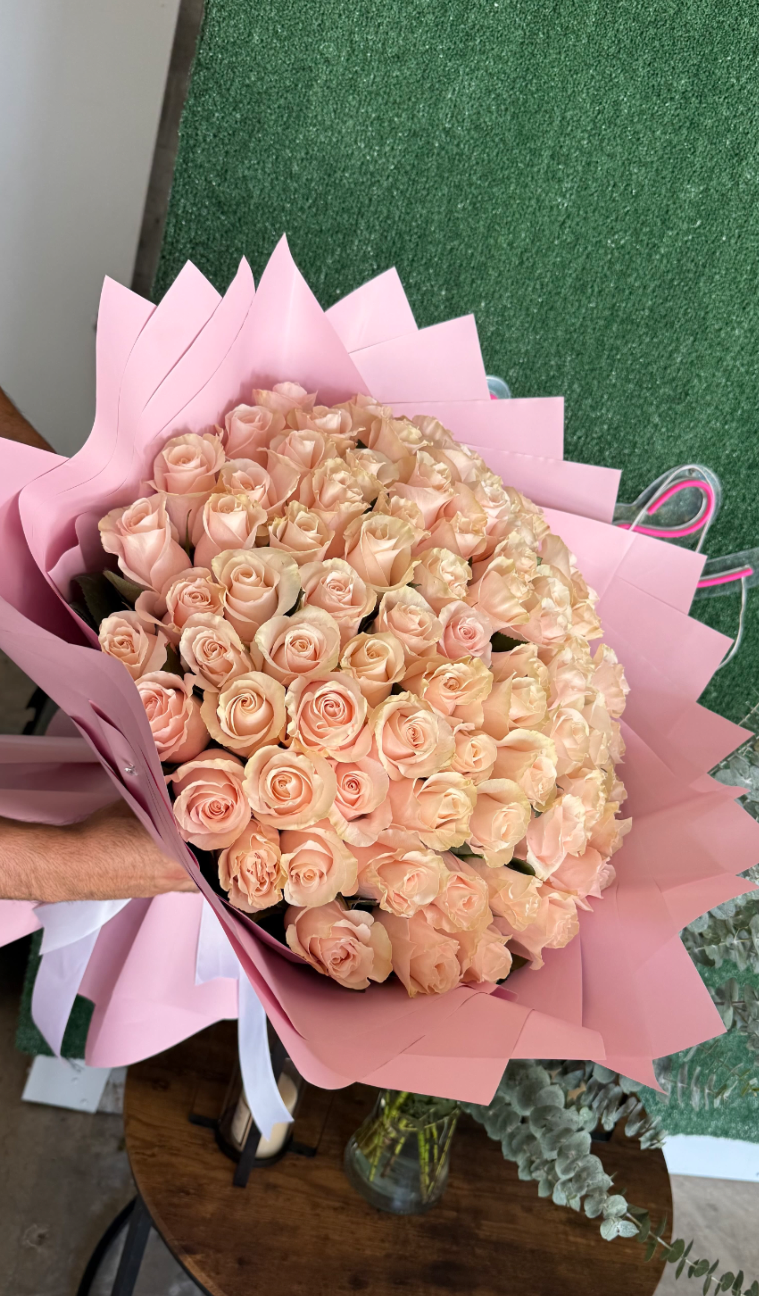 Large bouquet of pale peach roses wrapped in pink paper