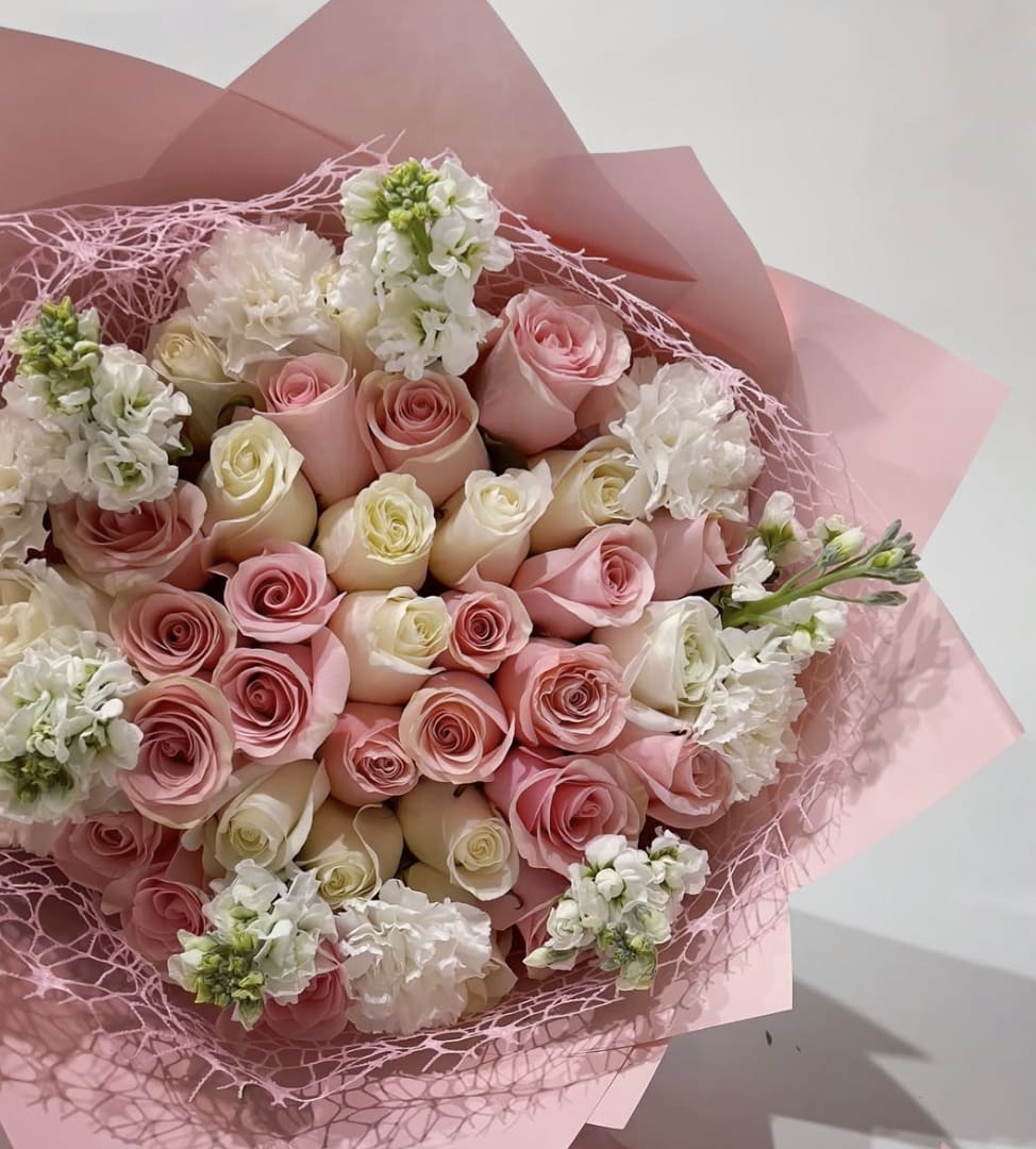 Bouquet of pink and white roses wrapped in pink paper