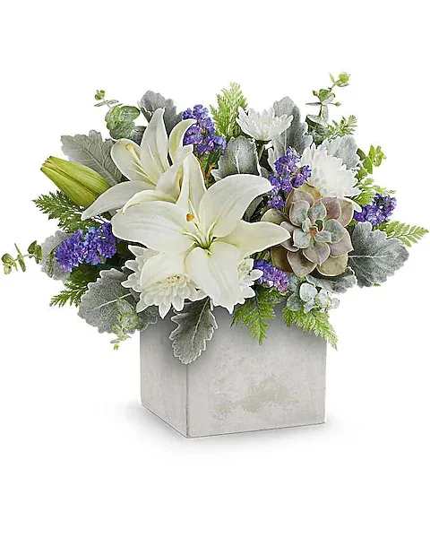 White lilies and purple flowers arranged in a square gray vase