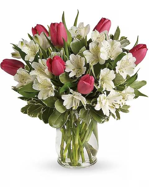 Pink tulips and white flowers arranged in a clear glass vase