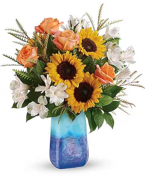 Sunflowers, peach roses, and white alstroemeria in a blue glass vase