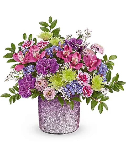 Mixed bouquet of pink, purple, and green flowers in a glittery lavender vase