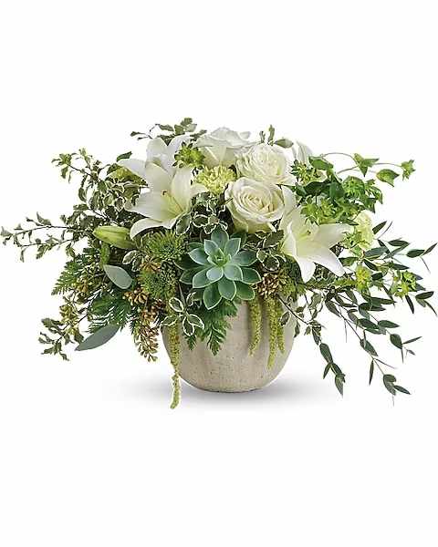White roses and lilies in a round stone vase with trailing greenery