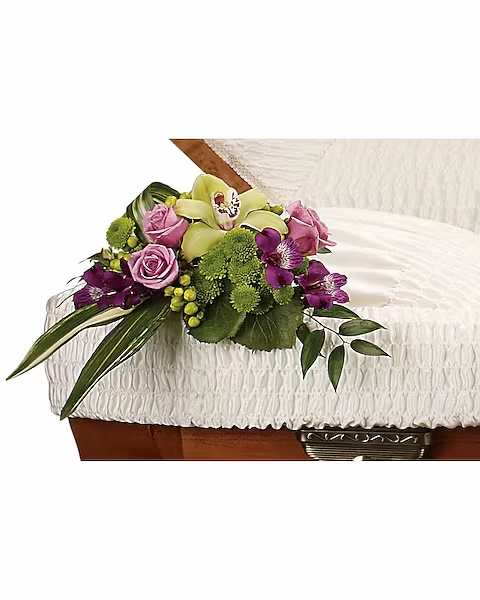 Pink and purple floral spray on a white casket