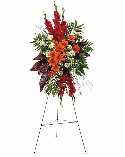 Tall floral standing spray with red and orange flowers on an easel