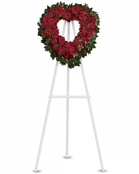 Heart-shaped red rose wreath on a white easel