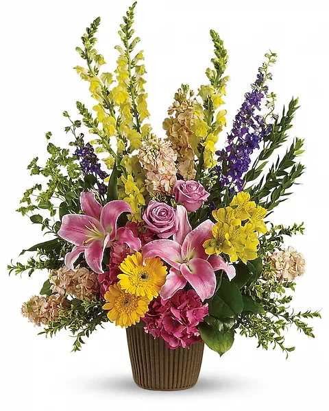 Mixed bouquet with pink lilies, roses, and yellow flowers in a brown vase