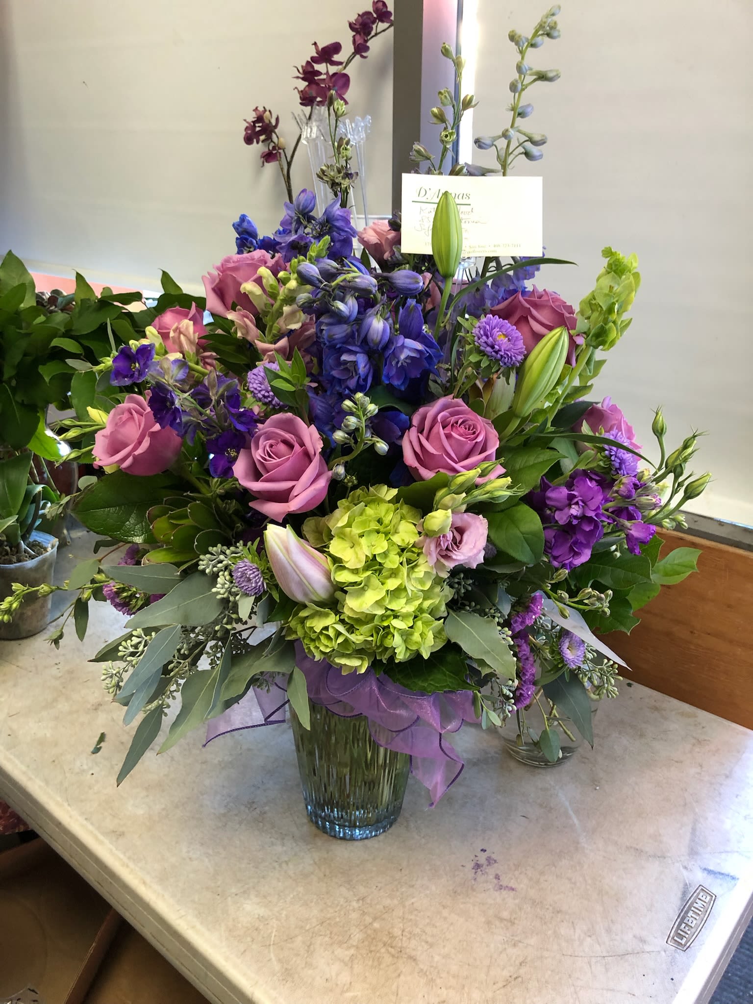 Mixed bouquet of purple, pink, and green flowers in a glass vase