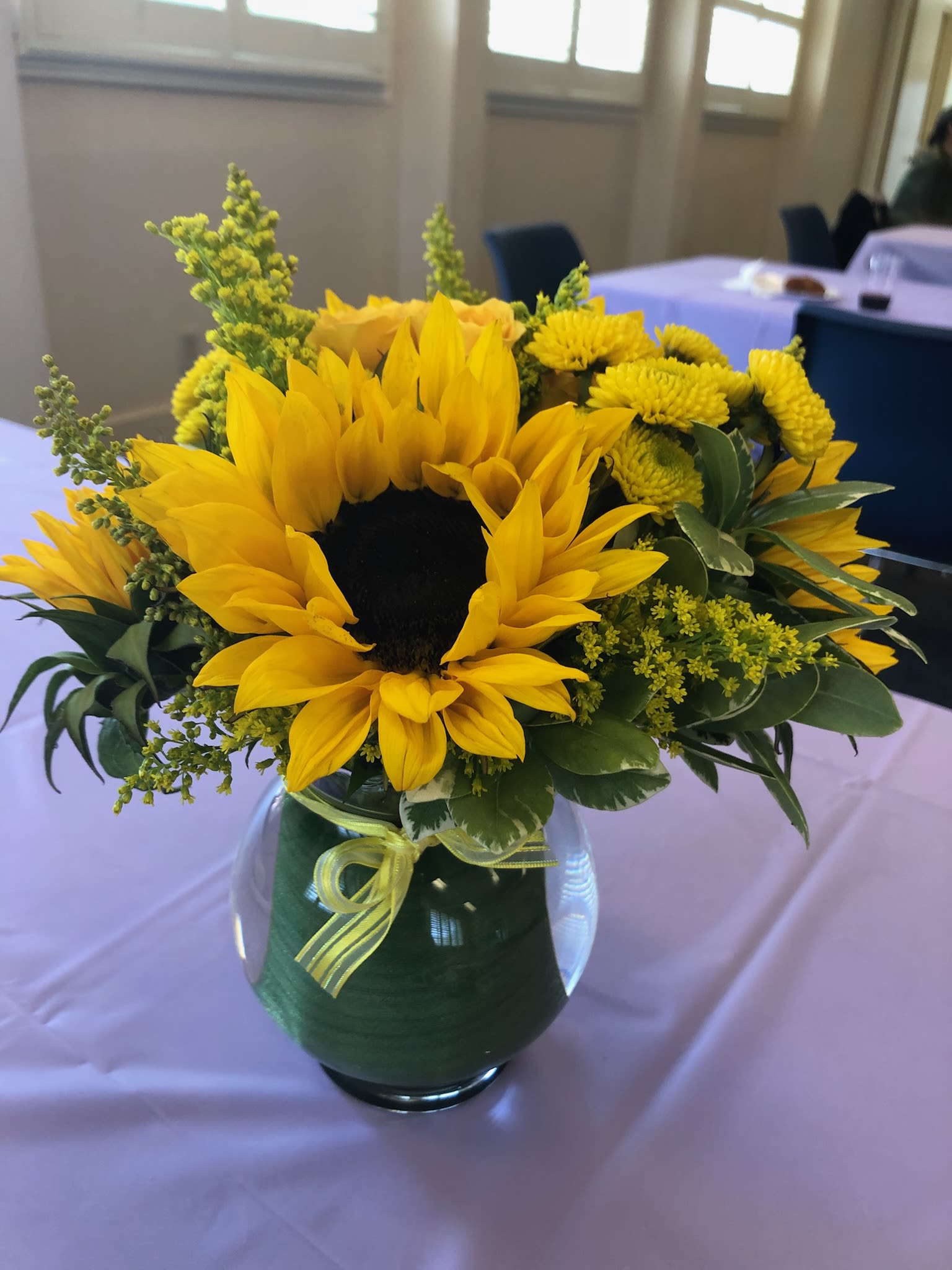 Yellow sunflower arrangement in a glass vase with a ribbon