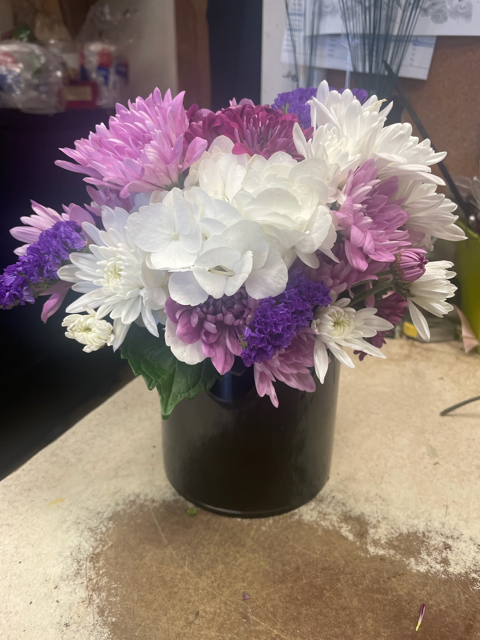 Bouquet of white, pink, and purple chrysanthemums in a black vase