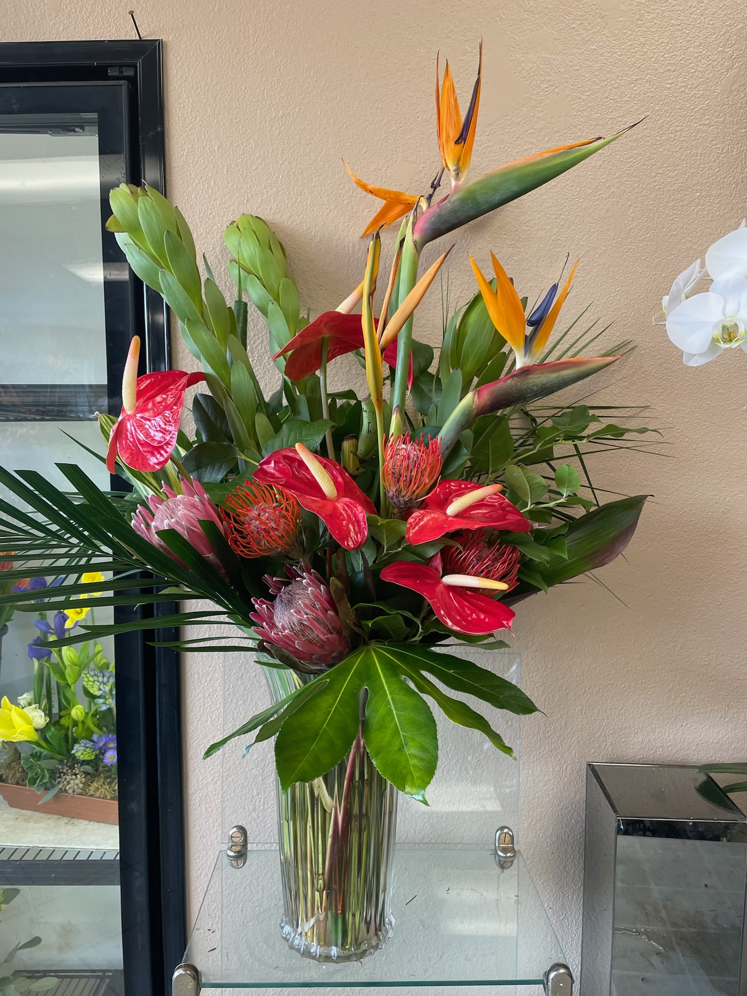 Tropical arrangement with red anthuriums and bird of paradise in a glass vase