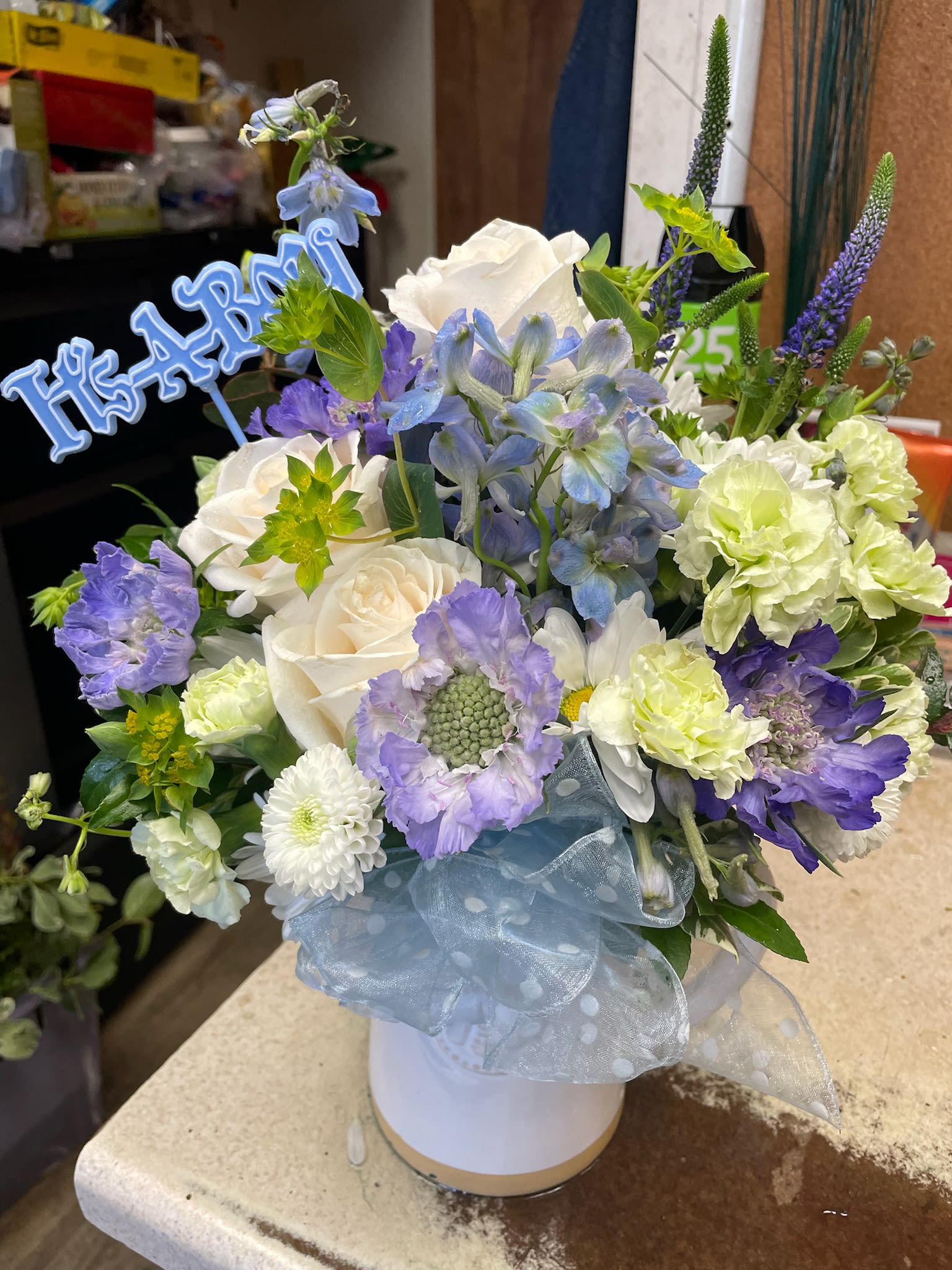 Blue and white floral arrangement in a white hatbox with a ribbon
