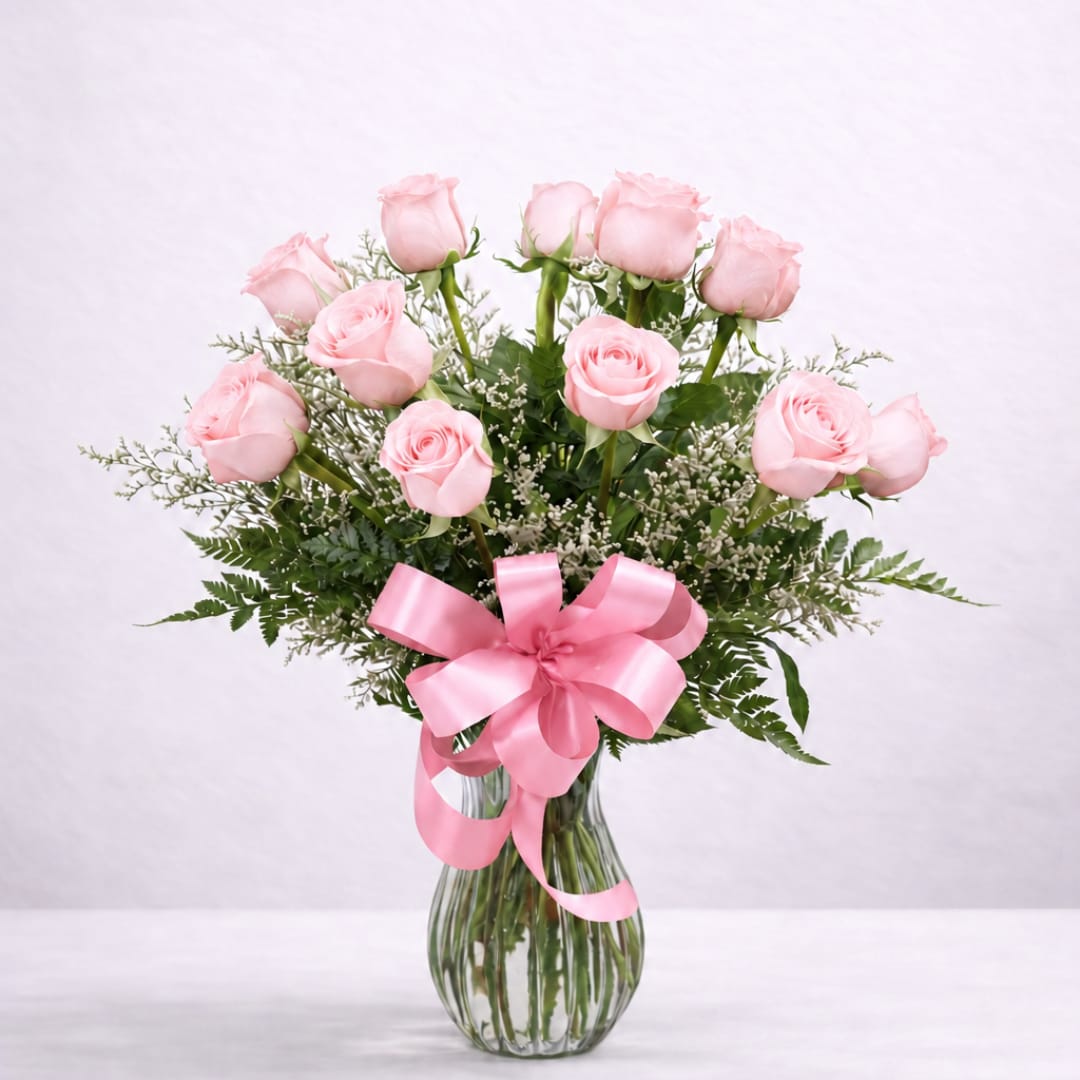 Pink roses in a clear glass vase with a pink ribbon