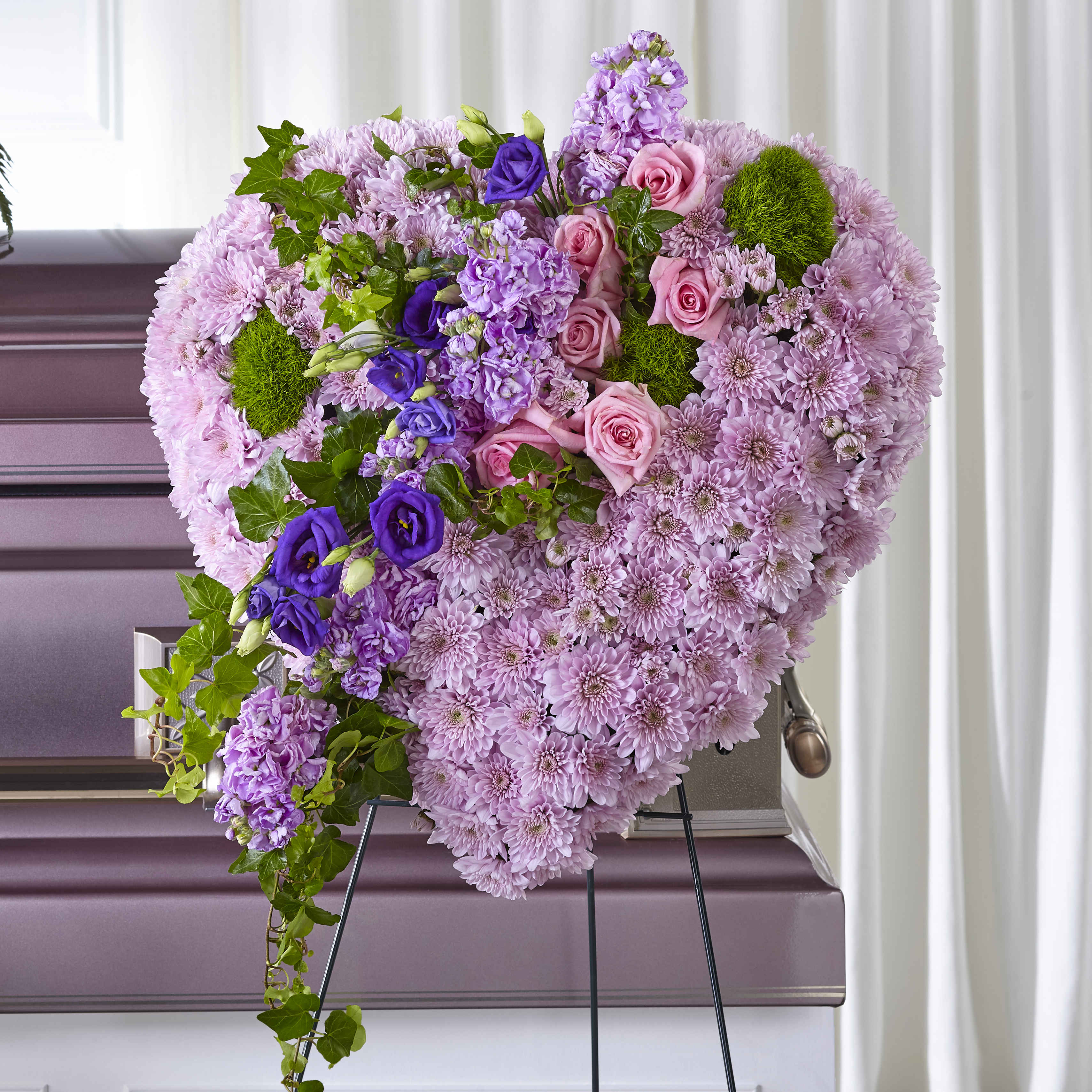 Heart-shaped floral arrangement with pink and purple flowers on a stand