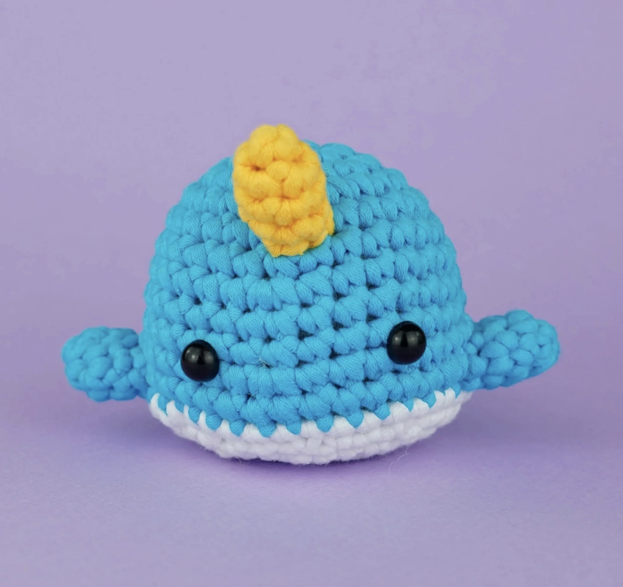 Crocheted blue whale plush with a yellow fin and white belly