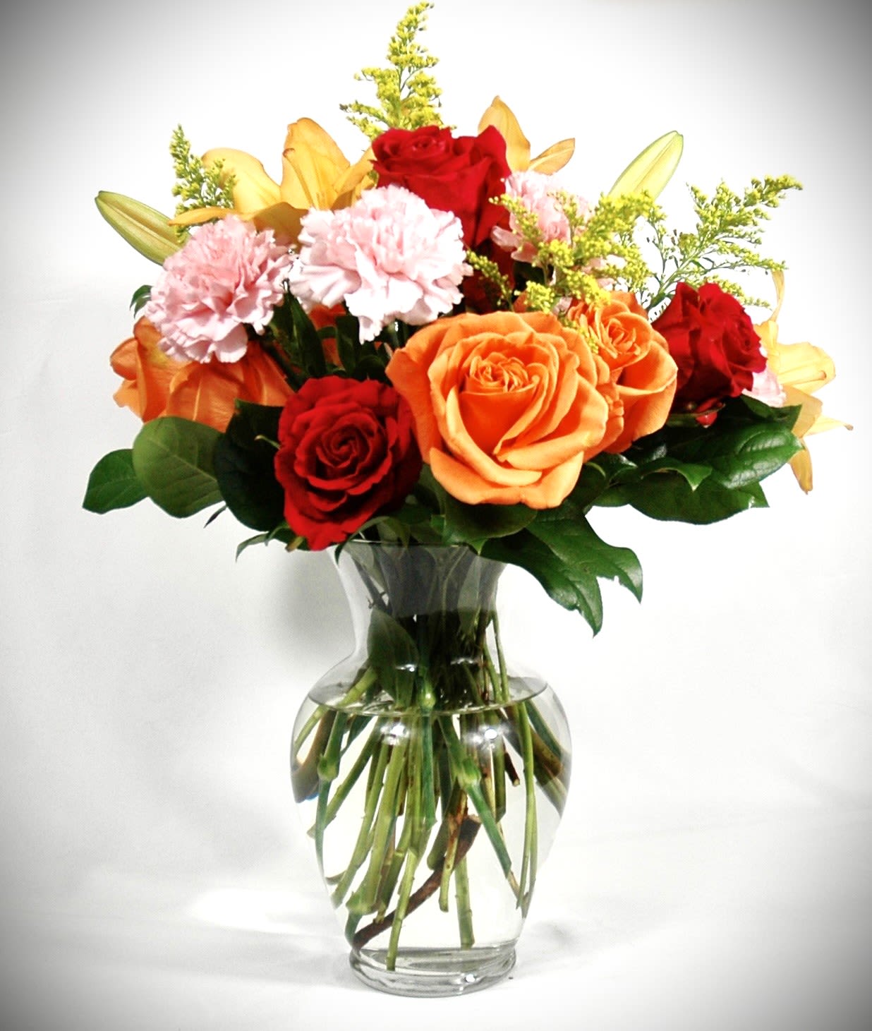 Party Popper - Bring the celebration to life with our bold and joyful Party Popper arrangement! Bursting with vibrant energy, this bouquet features dazzling red and orange roses, cheerful pink carnations, sunny yellow lilies, and radiant goldenrod, all nestled in a bed of lush, fresh greenery. Perfect for birthdays, celebrations, or any occasion that calls for a pop of color and joy, Party Popper is designed to light up any room and lift every spirit.  Vase subject to change