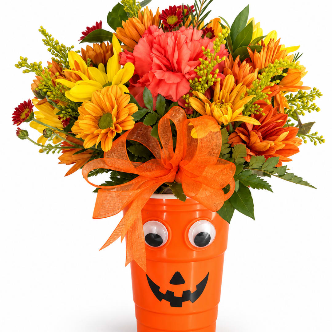 Orange Halloween bucket filled with mixed flowers and a ribbon bow