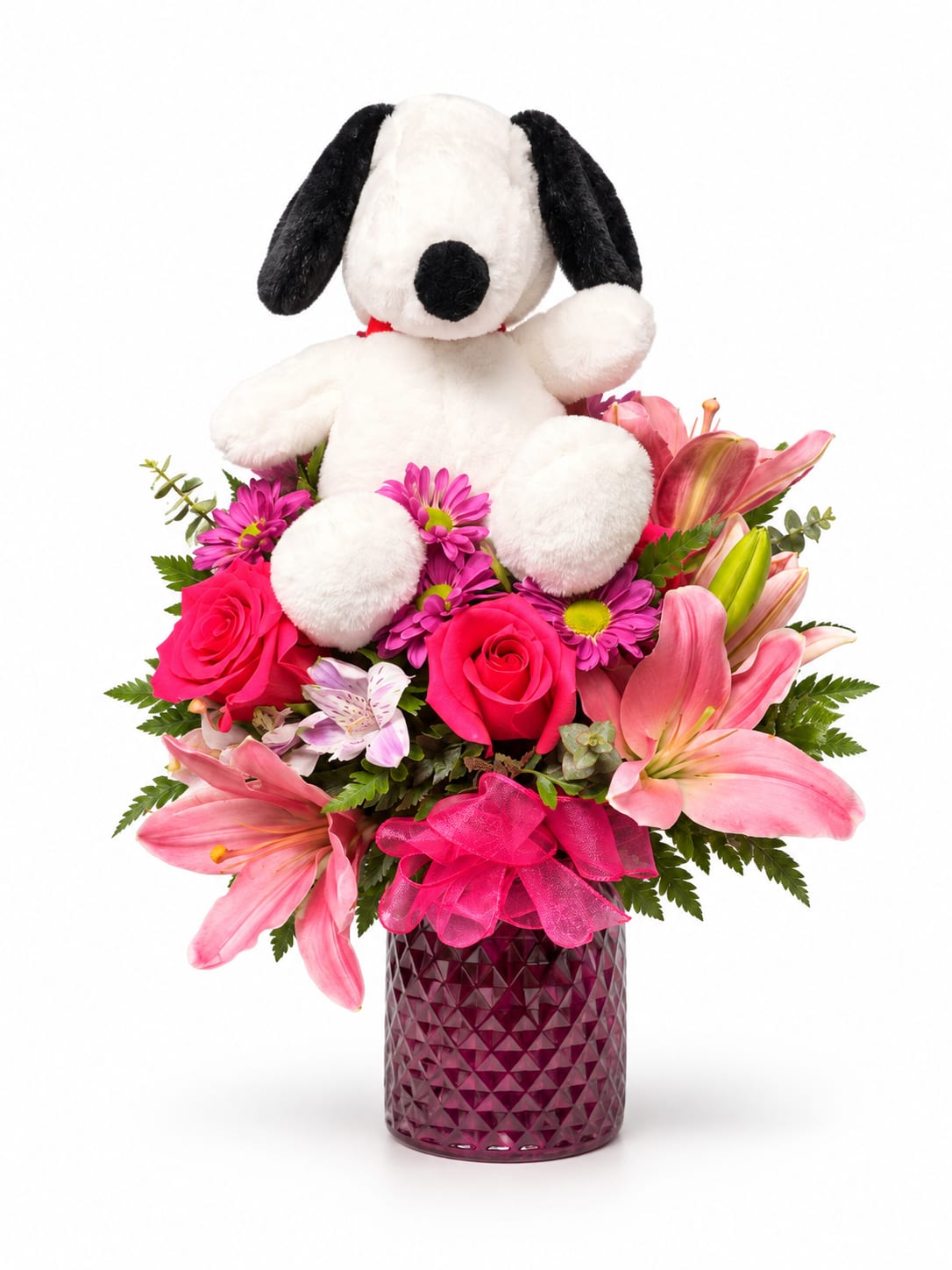 Plush dog sitting in a pink flower arrangement in a purple vase