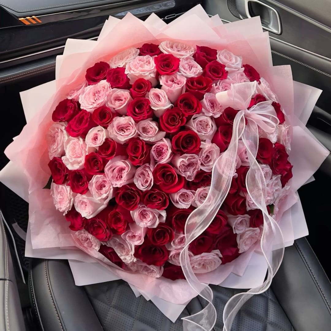 Bouquet of red and pink roses wrapped in pale pink paper with a ribbon