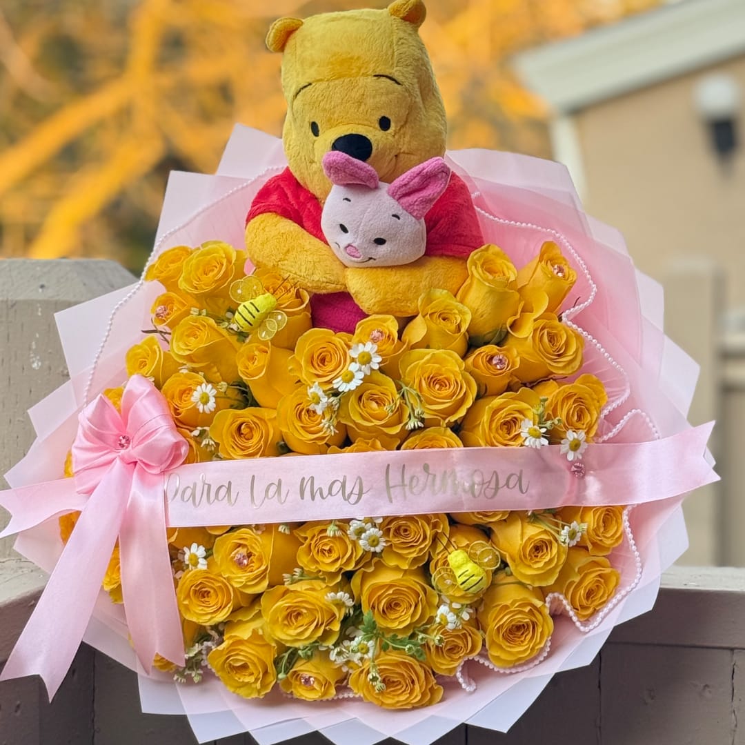 Bouquet of yellow roses with a Winnie the Pooh plush and pink ribbon