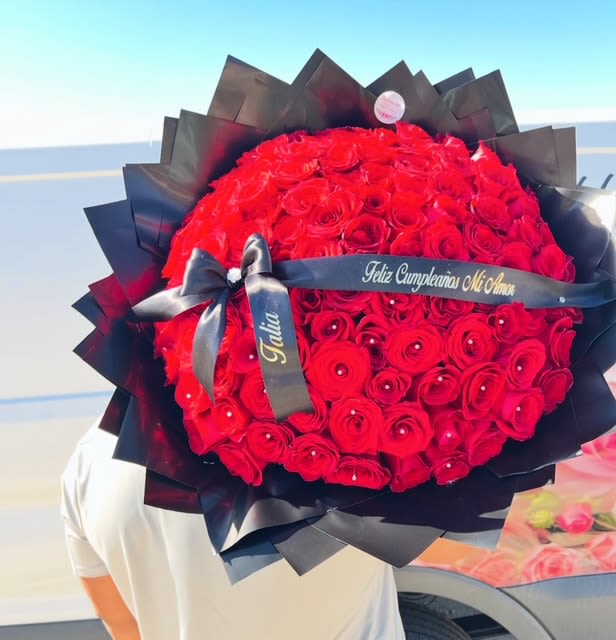Large bouquet of red roses wrapped in black paper with a ribbon