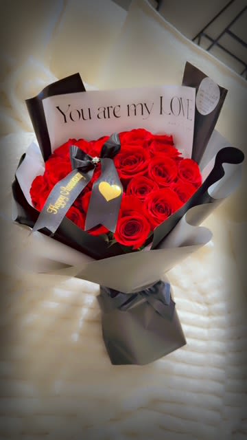 Bouquet of red roses wrapped in black and white paper with a love note