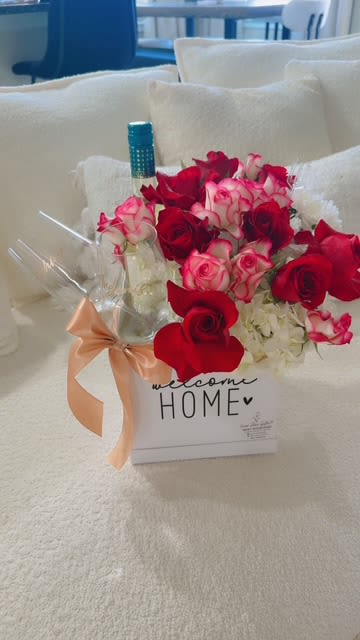 Box of red and pink roses with a wine bottle and ribbon