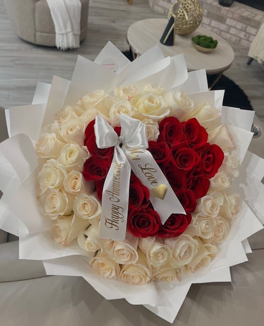 Bouquet of red and white roses wrapped in white paper with a satin bow